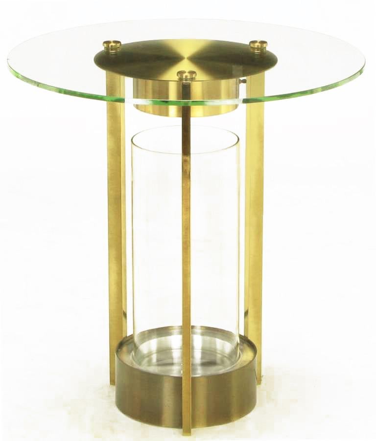 Unusual, yet very elegant, glass and brass end table with three legs, center glass cylinder terrarium and lighting element. One-half inch thick glass top is secured in three points with solid brass discs. Often attributed to Dorothy Thorpe.
 