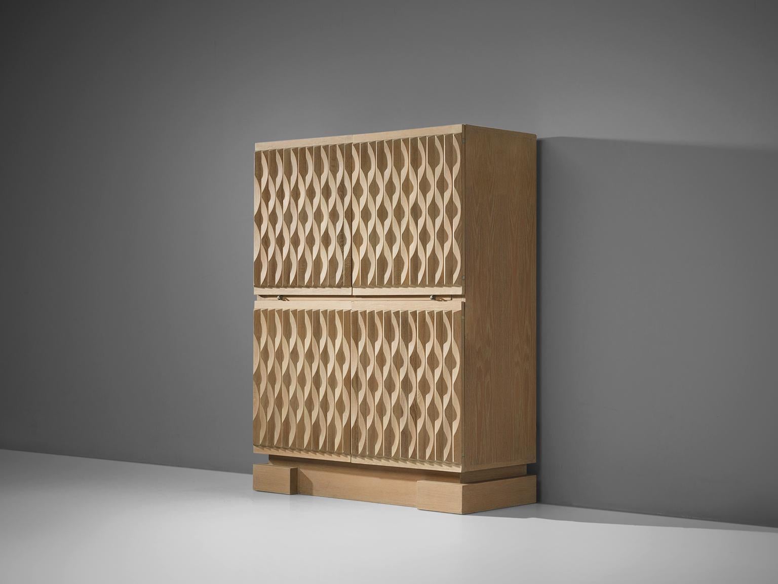 Brutalist cabinet, oak, Europe, 1970s. 

This illuminated cabinet with graphical door panels in blond oak. Four-door panels, each with an exceptional three-dimensional pattern. The continuous pattern gives this cabinet a very strong expression,