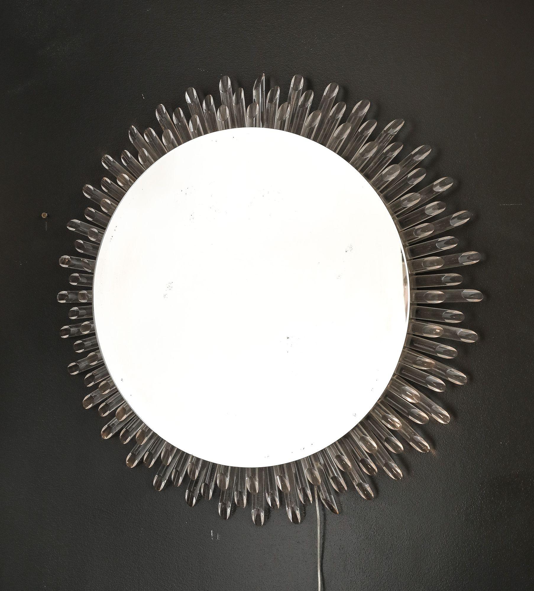 A dazzling Mid-Century Modern sunburst mirror, circa 1985, featuring three tiers of radiating lucite rods that capture and refract light. The circular mirror plate at the center measures 19.5 inches in diameter, while the overall piece, with its