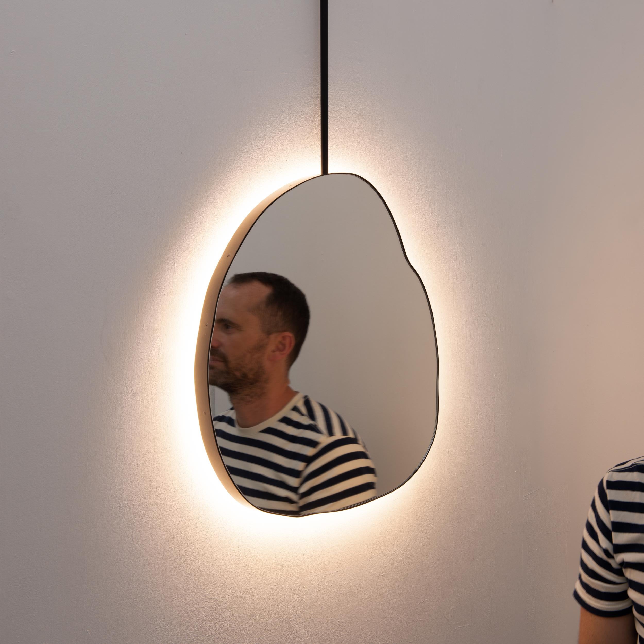 Original and unique organic shaped Ergon™ suspended mirror with a modern matte black frame. The back-illumination creates a beautiful mood light when installed in front of a wall.

Designed and handcrafted in London, UK, our unique and elegant