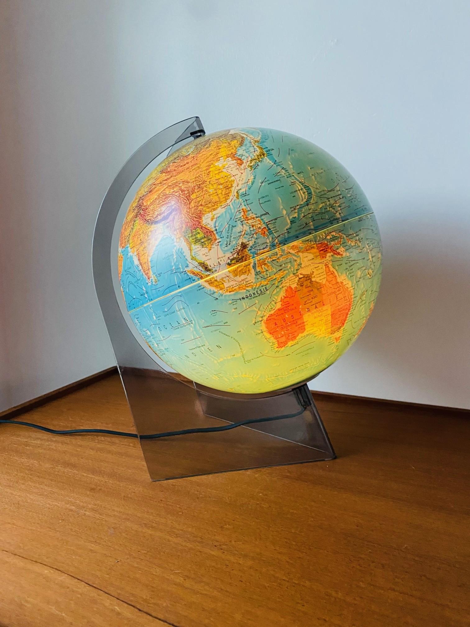 Beautiful illuminated French edition globe. This piece is magical, glamorous and chic. The aerodynamic lucite base holds the beautiful blue globe that when illuminated reveals in the most magical and artistic form. Cartography for this piece is by