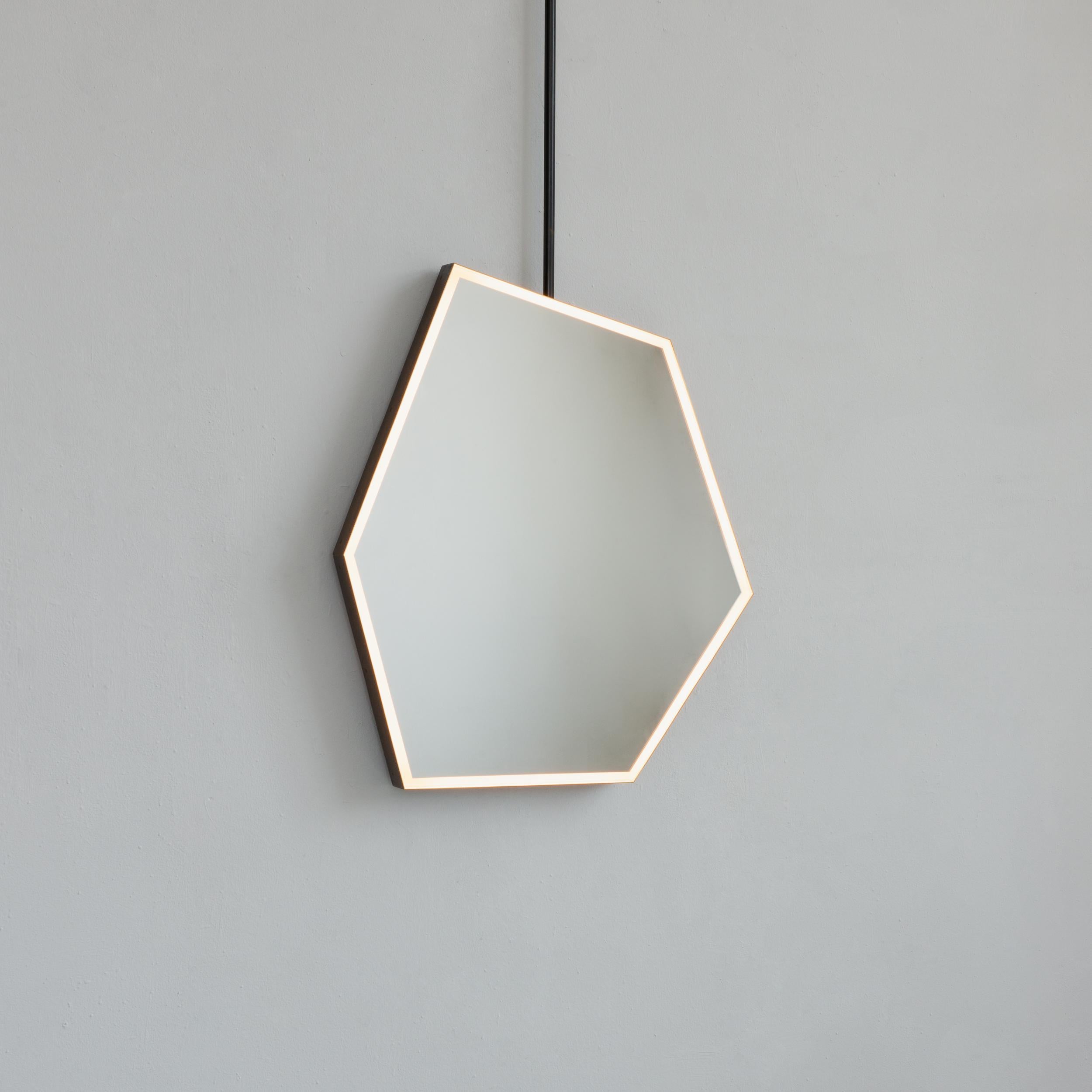 Modern and unique irregular hexagon suspended mirror with an exquisite and handcrafted brass frame with bronze patina finish. 

The mirror has an original and decorative front-illumination feature that has the potential to create a beautiful mood