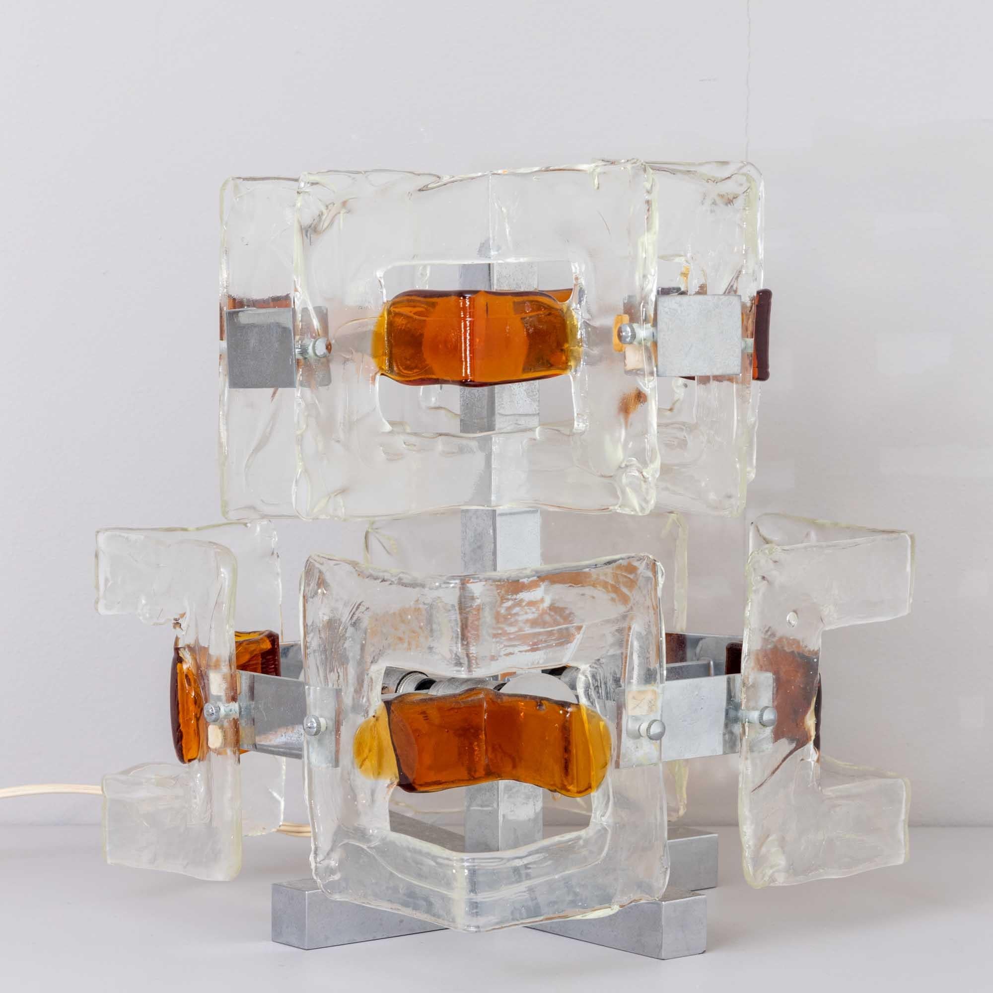 Illuminated Italian Art Glass sculptural table lamp.
Clear and amber glass forms mounted on a chrome plated metal frame.
