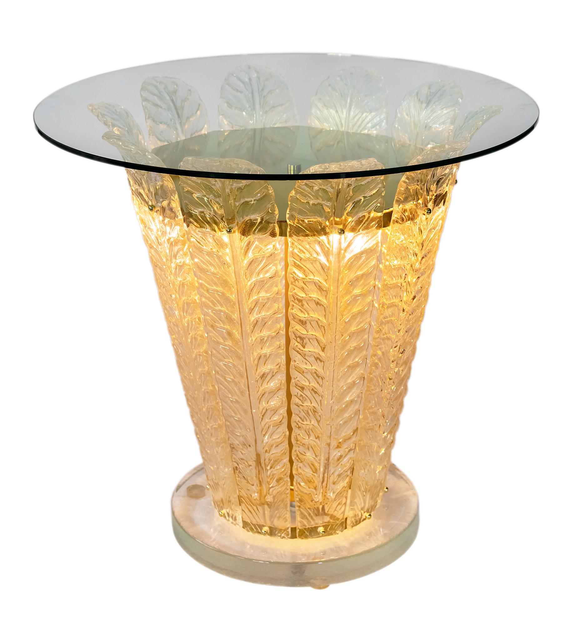 This side table is illuminated as created with the lighting function inside.
The base is a very thick solid glass, decorated with handmade Murano glass leaf form details and tempered glass top.
The are 3 pcs. of E27 bulbs inside.
 