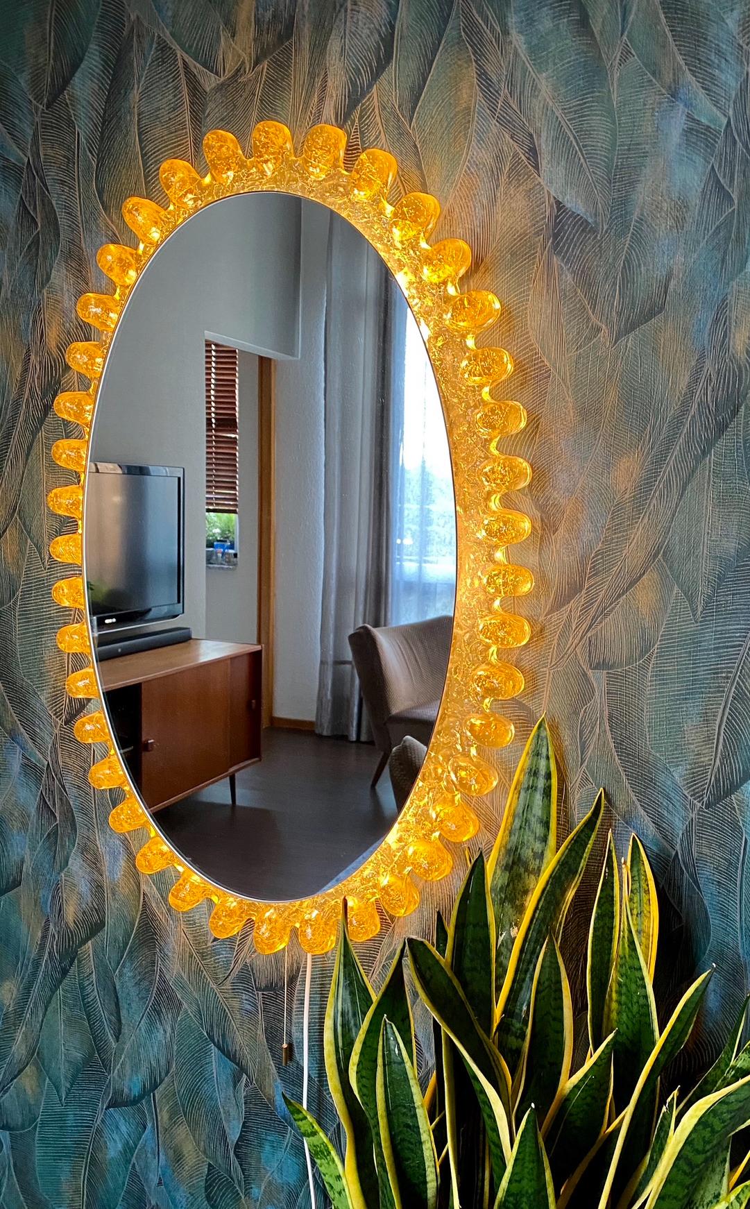 A wall mirror with indirect lighting from the German manufacturer Hillebrand Lighting. It was manufactured in Germany in the 1970s. The mirror frame is made of acrylic and the base is made of metal. Perfect for a dressing room, bedroom, or living