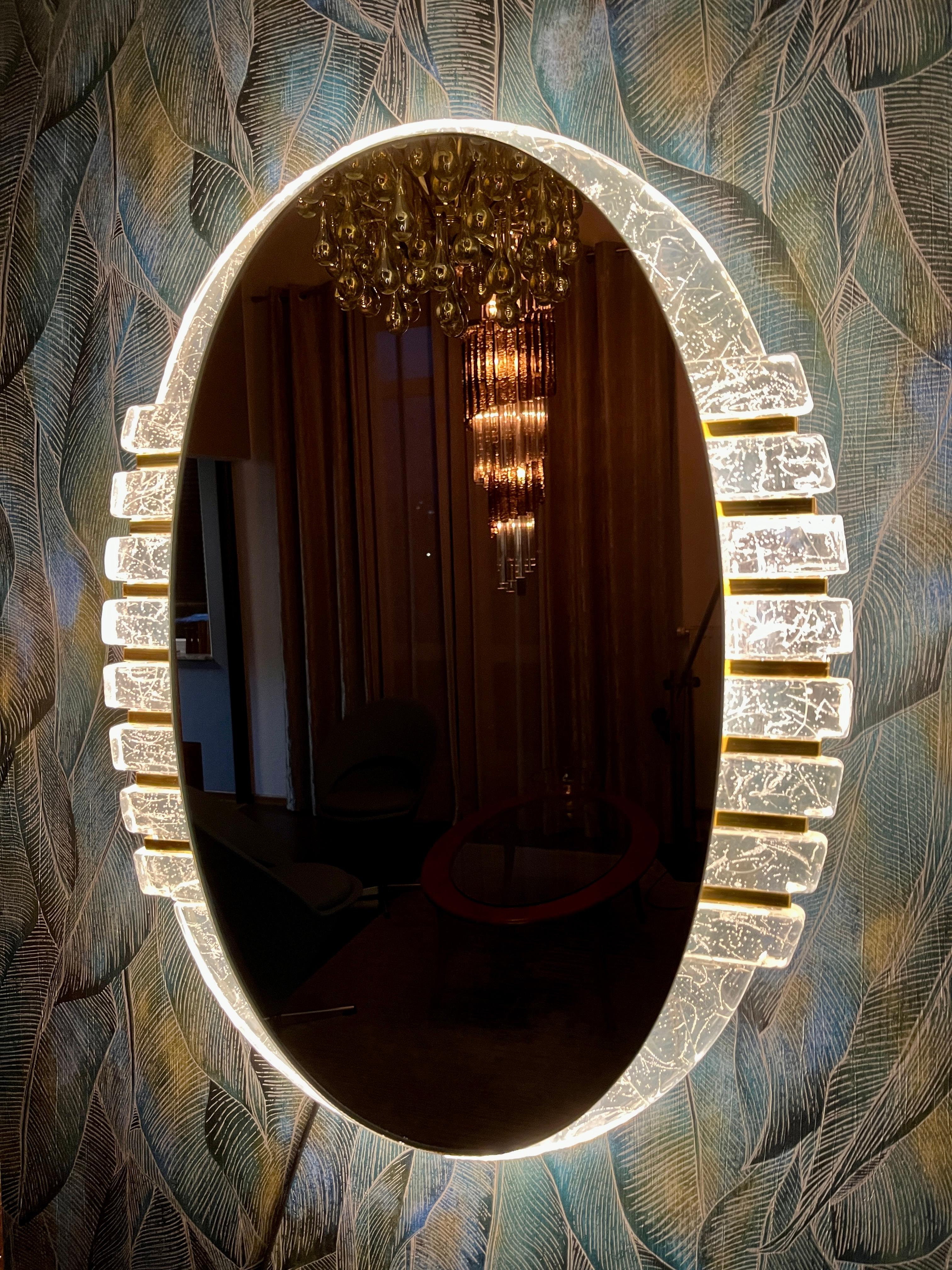 A wall mirror with indirect lighting from the German manufacturer Hillebrand Lighting. It was manufactured in the 1970s. The frame contains four E14 light bulbs (max. 40W). The mirror frame is made of acrylic, and the frame is made of metal.

This