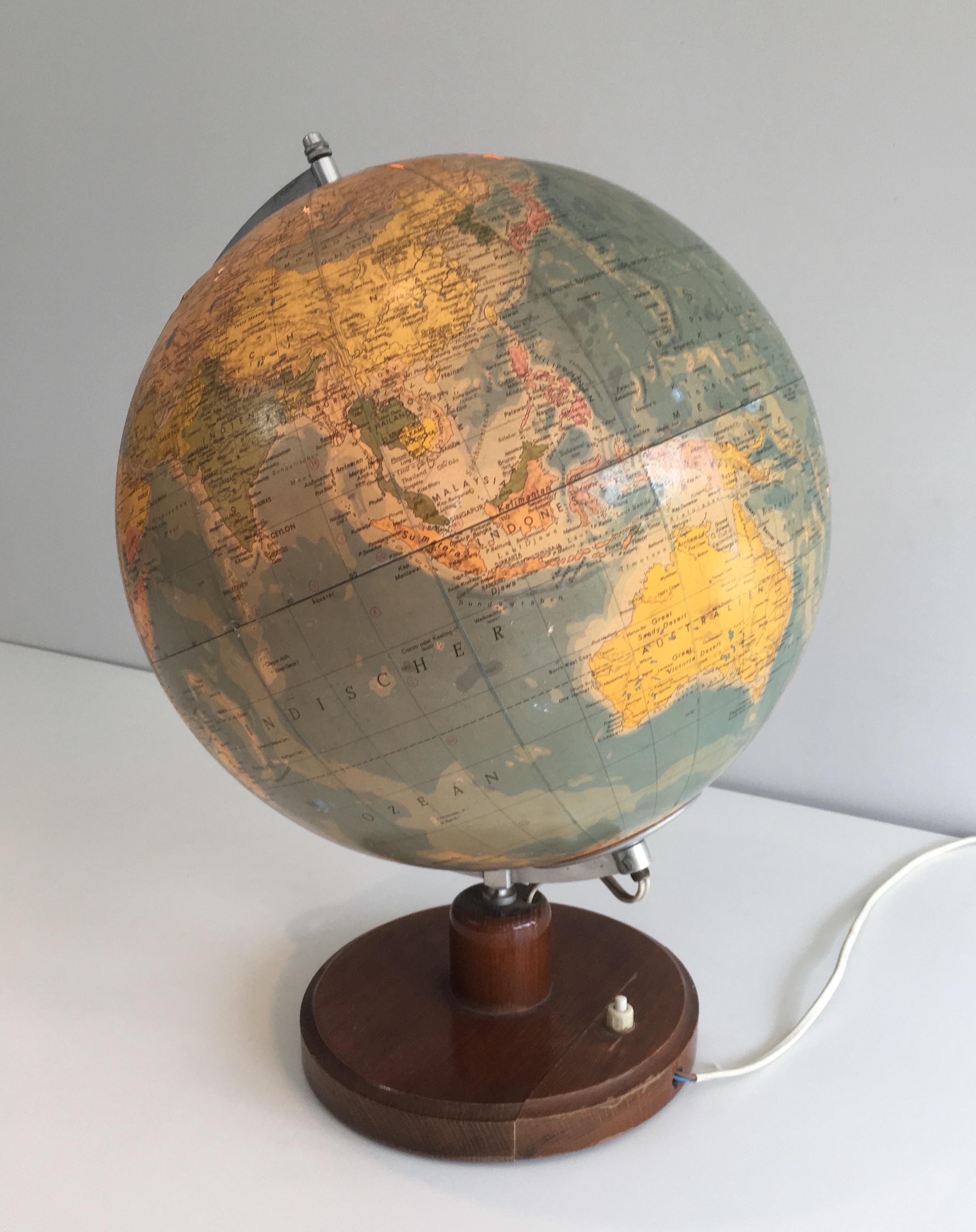 This illuminating globe is made of paper on plastic, metal and wood. This is a German work, circa 1950.