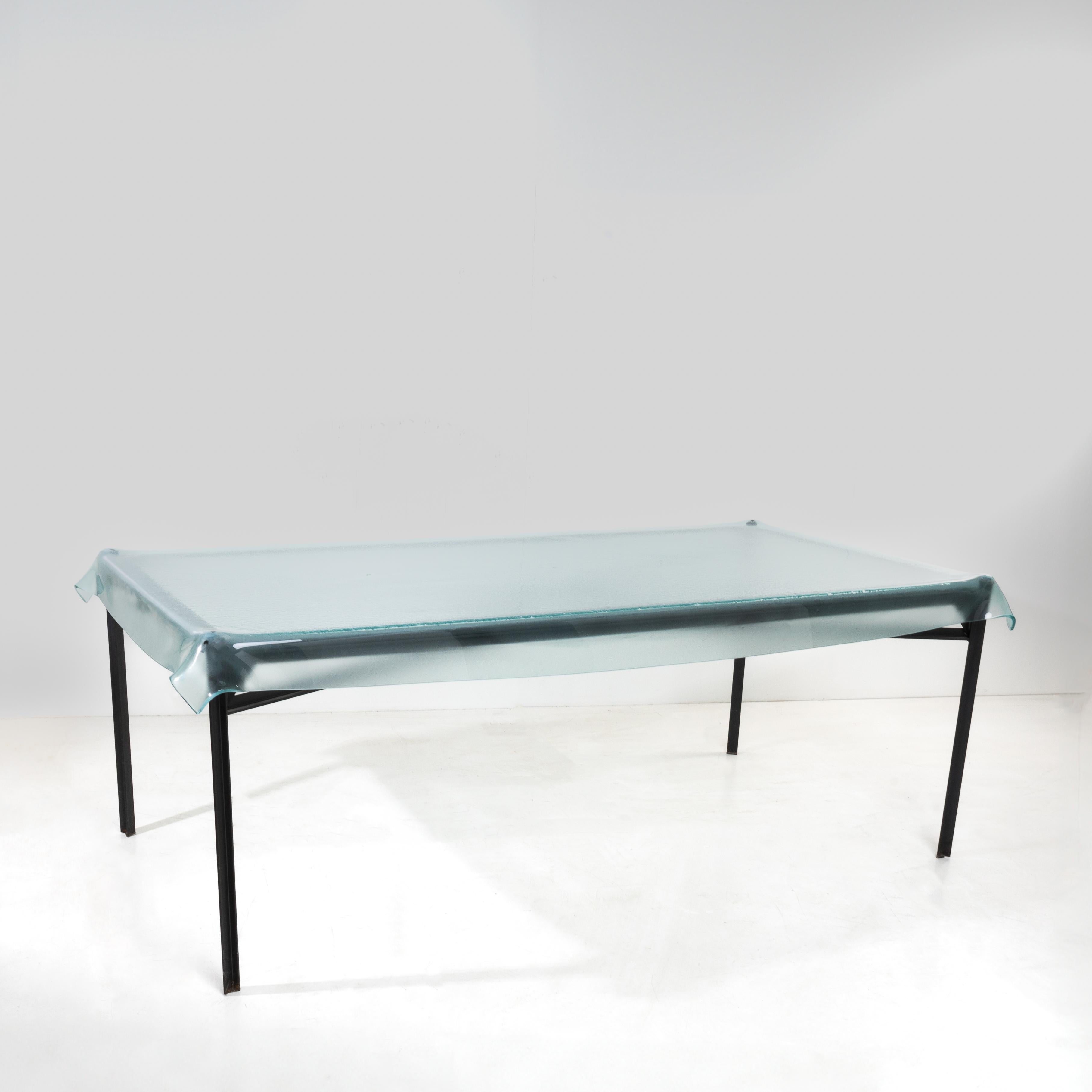 “Illusion” dining table by Philippe Starck, Fiam (Italy).
Steel and bronze structure.
Molded glass top giving the illusion of a tablecloth placed on the base.

Description taken from the website of the Museum of Paris Decorative Arts:
Trained at the