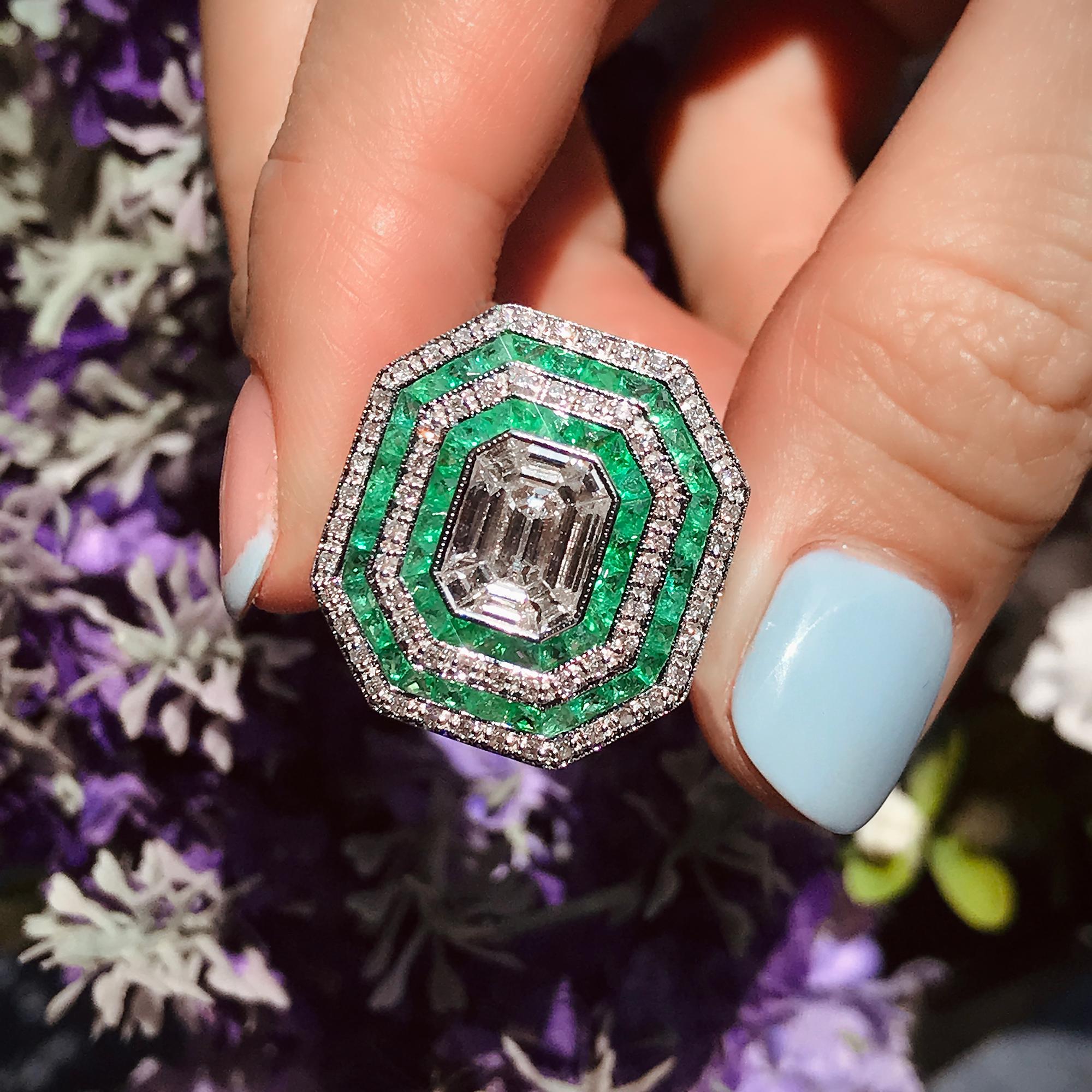 The elegant center of this ring features multiple diamonds formed an emerald shape by illusion setting with a total of .79 carat G color, VS clarity diamond framed by four rows of French cut emeralds and shimmering round diamonds. A stunning Art