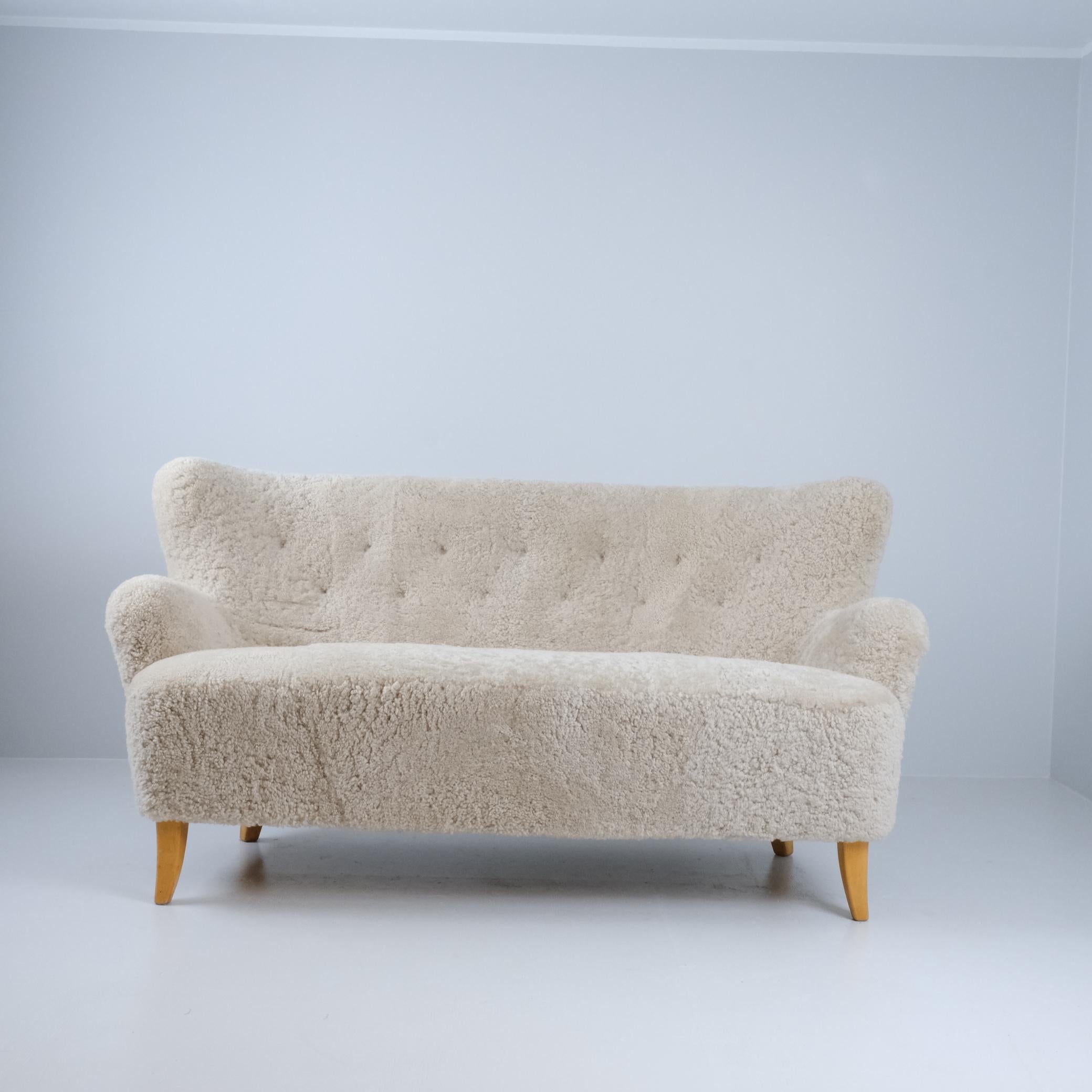 An elegant sofa designed by Ilmari Lappalainen and manufactured by Asko Oy in Finland in the 1940s. The sofa is reupholstered with natural sheepskin and apart from the reupholstery the sofa is in original and very good condition. 

The sofa is very