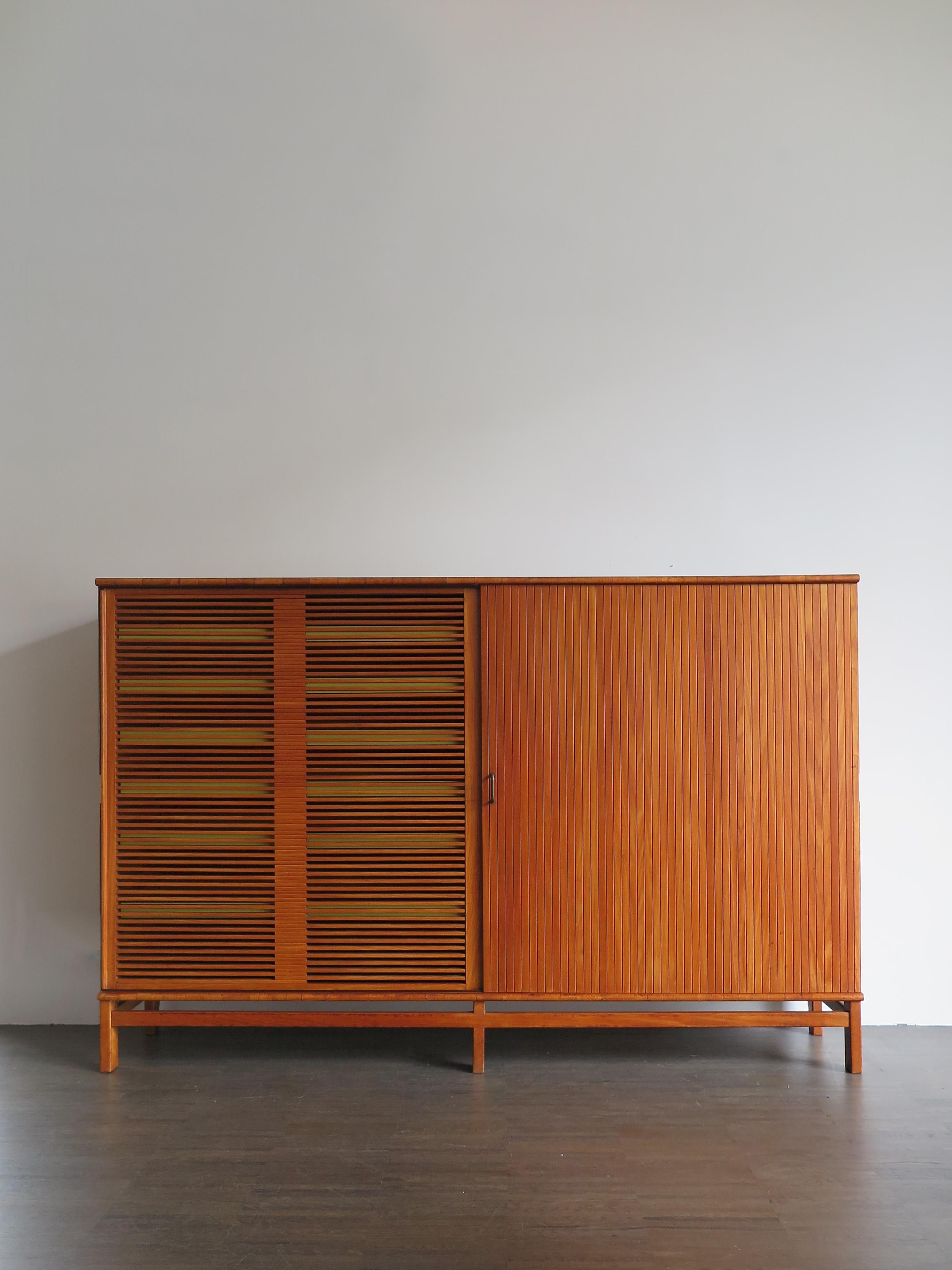 Midcentury modern design large chest of drawers or cabinet, designed by Finnish designer Ilmari Tapiovaara for Selettiva di Cantù, wooden structure with two large sliding doors and modular drawers with yellow formica front and brass detail at the