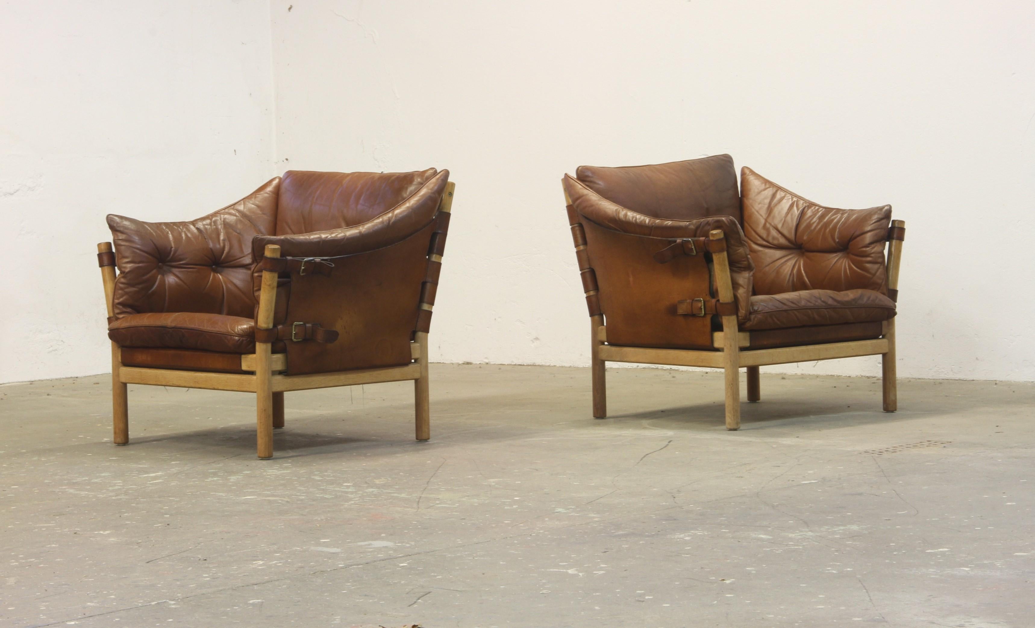 Maskuline leather chairs designed by Arne Norell in the 1960s, produced in Sweden. Featuring thick brown leather cushions on saddle leather sling supports with brass hardware, the sturdy beech wood frame enhances their bold presence.

Perfect around