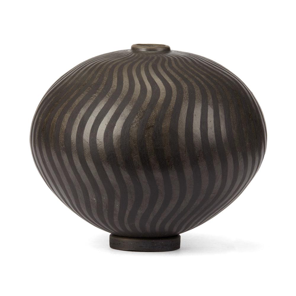 A stunning Czech, Ilona Sulikova raku fired black and black ceramic studio pottery vase with small circular stand. The rounded vase has a narrow raised neck and is burnished before application of copper carbonate which creates a shiny and matte