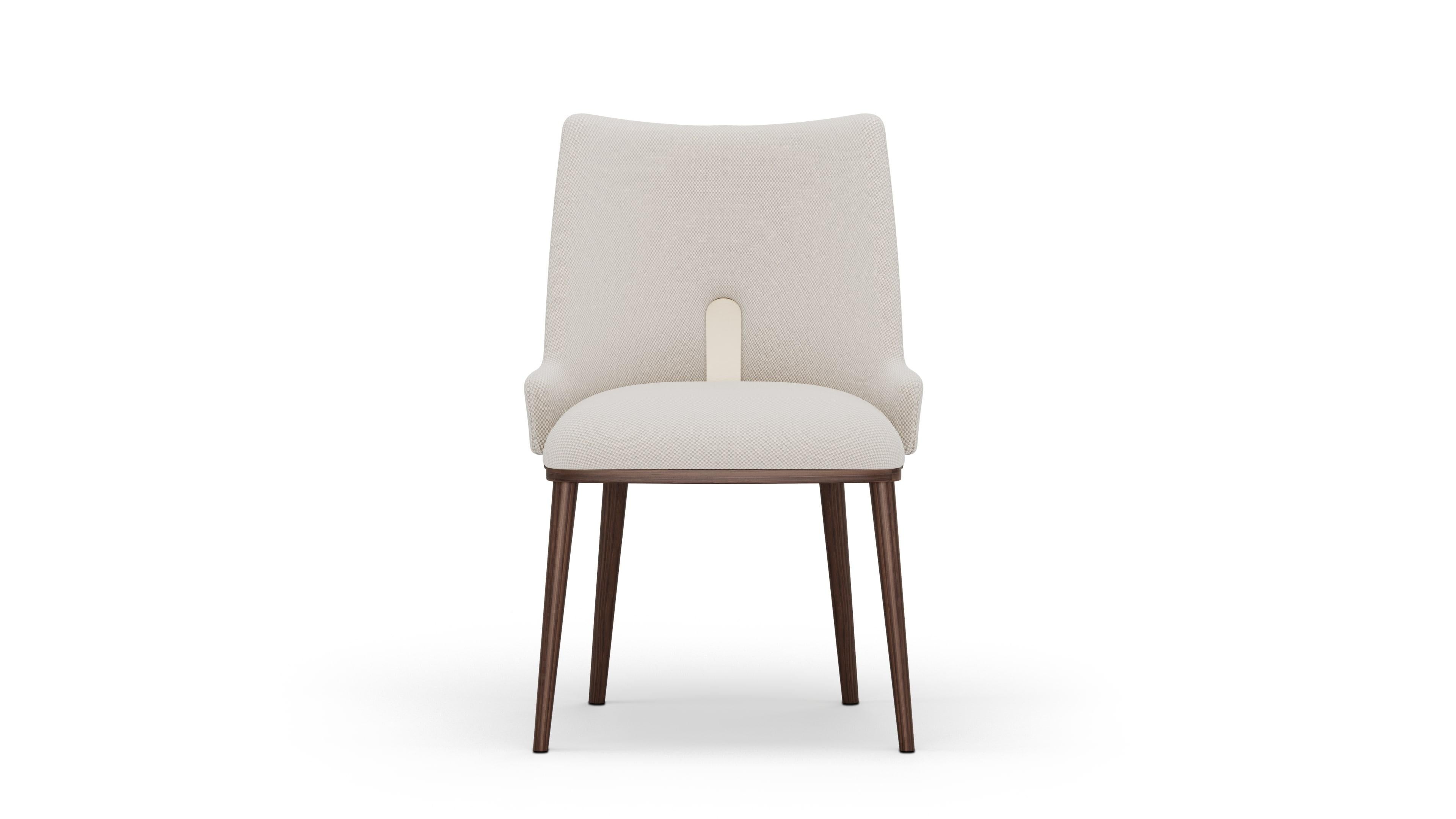 Ilora chair is a refined expression of modern elegance, where clean lines meet subtle detail. Wrapped in soft cream fabric, the chair’s silhouette is graceful yet grounded, supported by solid walnut legs that showcase the warmth of natural wood. A