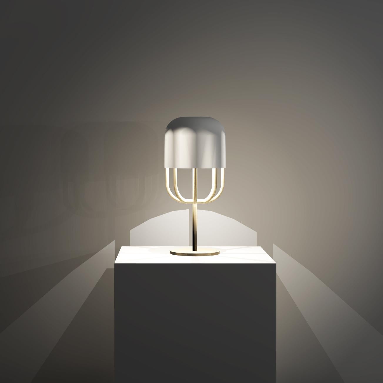 Cette lampe à poser présente un design audacieux qui utilise la symétrie entre l'enveloppe extérieure et le cadre d'une forme de capsule. La douce lueur du verre opale est élégamment soutenue et mise en valeur par une belle structure en laiton