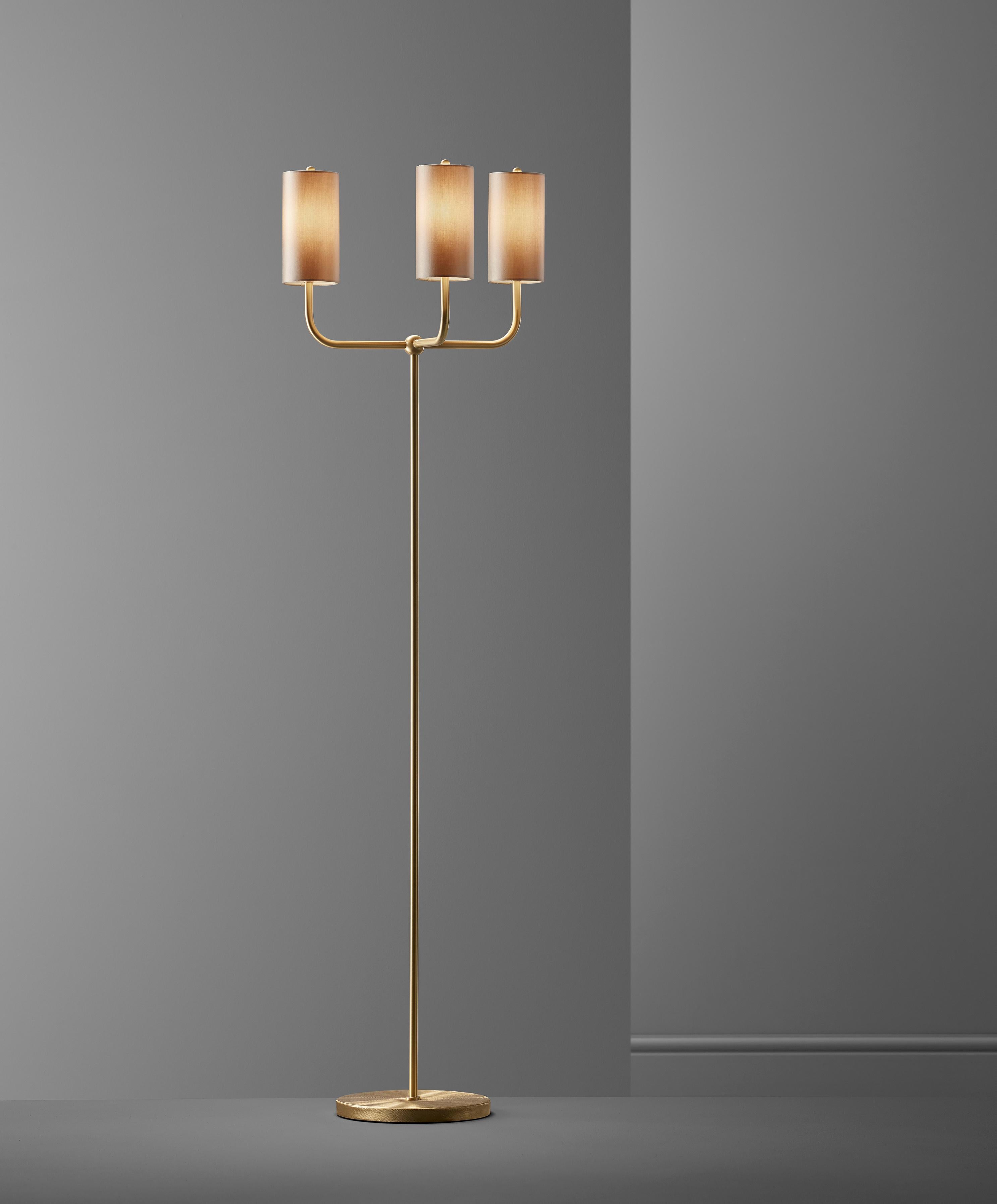 This floor lamp is a modern take on tradition. Beautifully crafted with elegant materials including brushed brass and sateen shades. The tall, timeless shades add a modern touch to the classic motif base, giving a familiar, yet forward looking