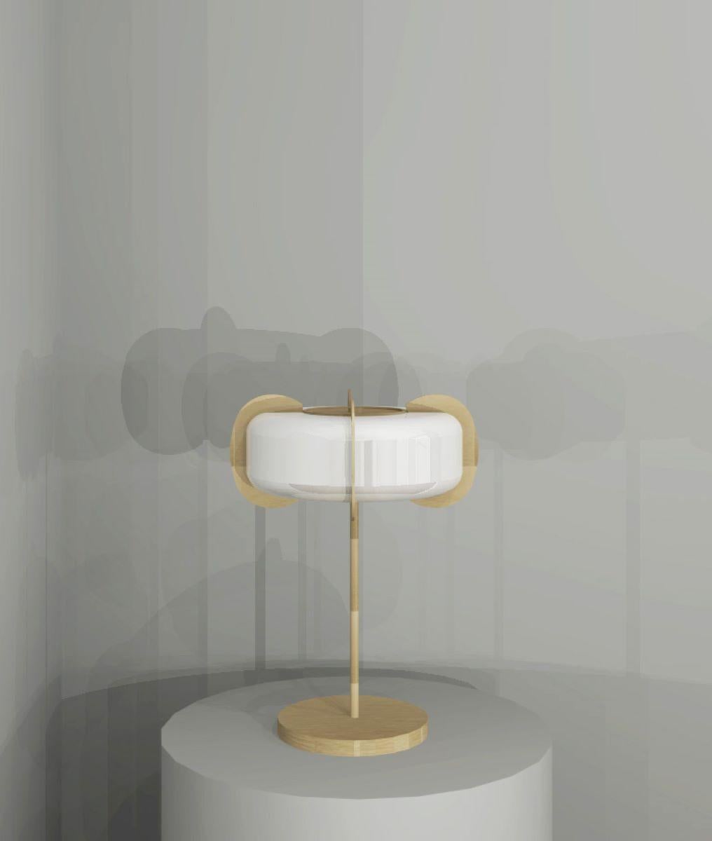 Art Deco form, but Minimalist design remains. This table lamp is crafted from solid brass and white glass. A sculptural design formed from elegant oval frosted glass shade with brushed brass discs connected to the top and bottom diffusers that go