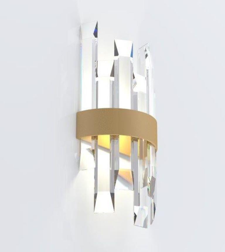 This wall light uses a mix of bold materials, brushed brass band and over-sized crystal elements, to give impact whilst remaining clean and classic. The designs cool, clean, beveled-edge crystals give a beautiful reflection and transparency, whilst