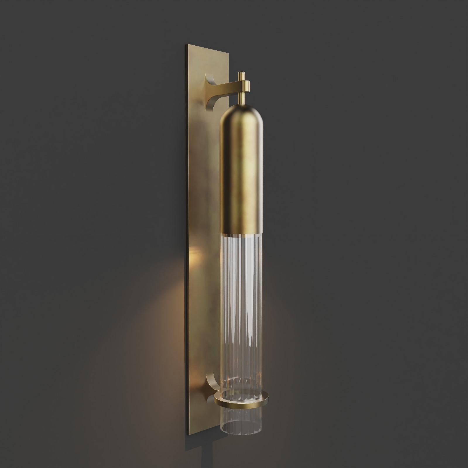 Wall Light in  brushed brass metal finish with fluted glass shade. 

Dimensions:
Overall Height: 550mm 
Glass Dia: 60mm 
Overall projection: 108mm 
Backplate Width: 80m
Integrated LED

Made to order to buyer's specification. Variations to dimensions