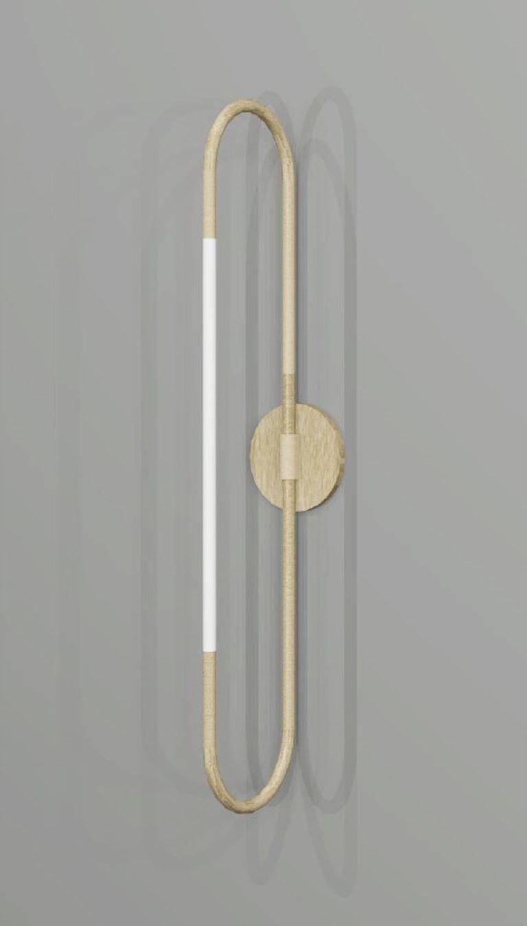 This wall light is based on infinite loops of brass, coiling continuously to create a free and fluid structure, with subtly integrated lighting elements.
Finishes: brushed brass and opal glass.

Height: 530mm
Projection: 100mm
Rod Dia: 15mm

Made to