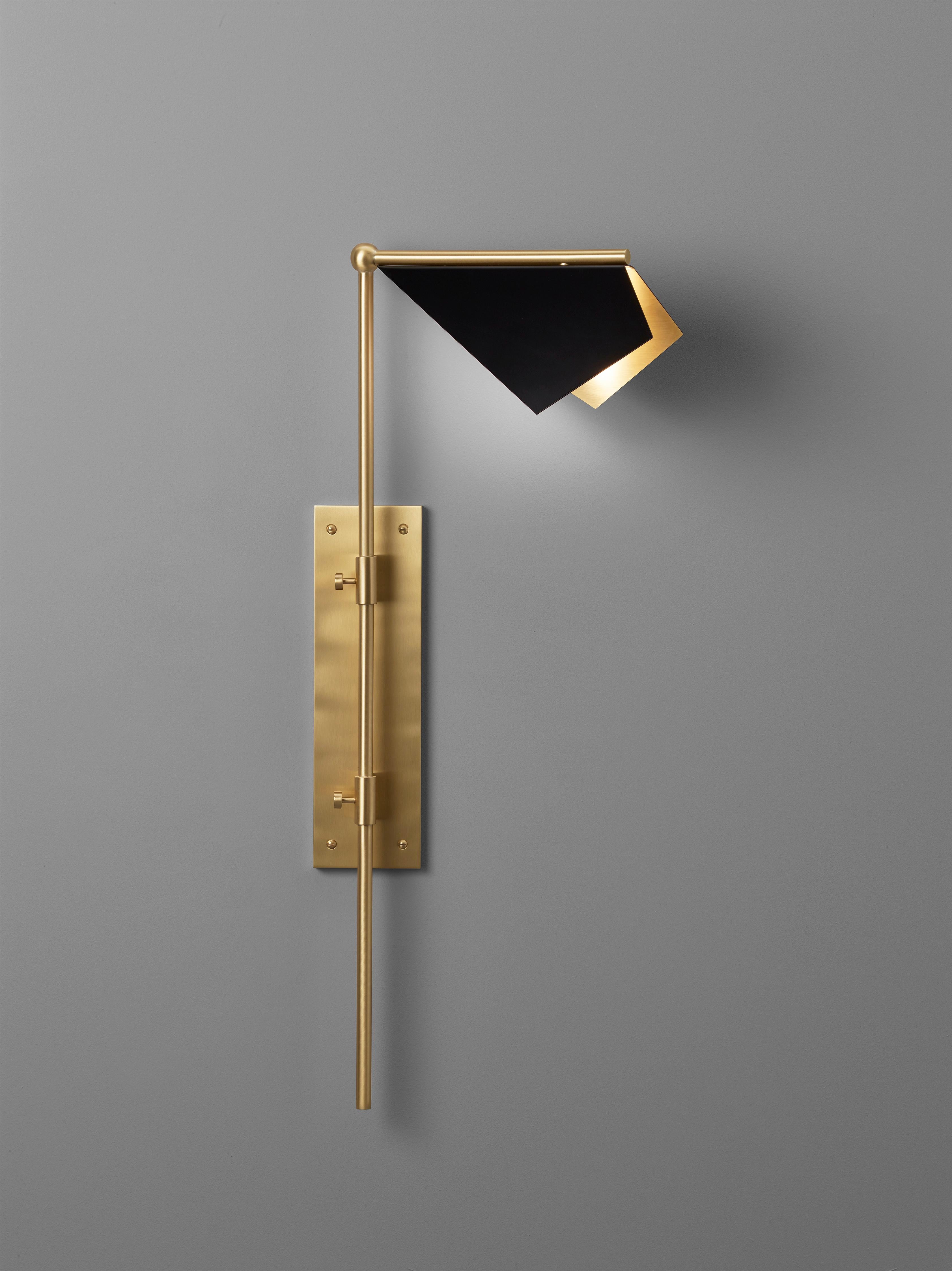 Design and crafted by world-renowned lighting brand IMAGIN, and inspired from observing bats while on vacation, this wall light combines a simple folded brass shade along with a long arm brass base. The topside of the shade finished in matt black