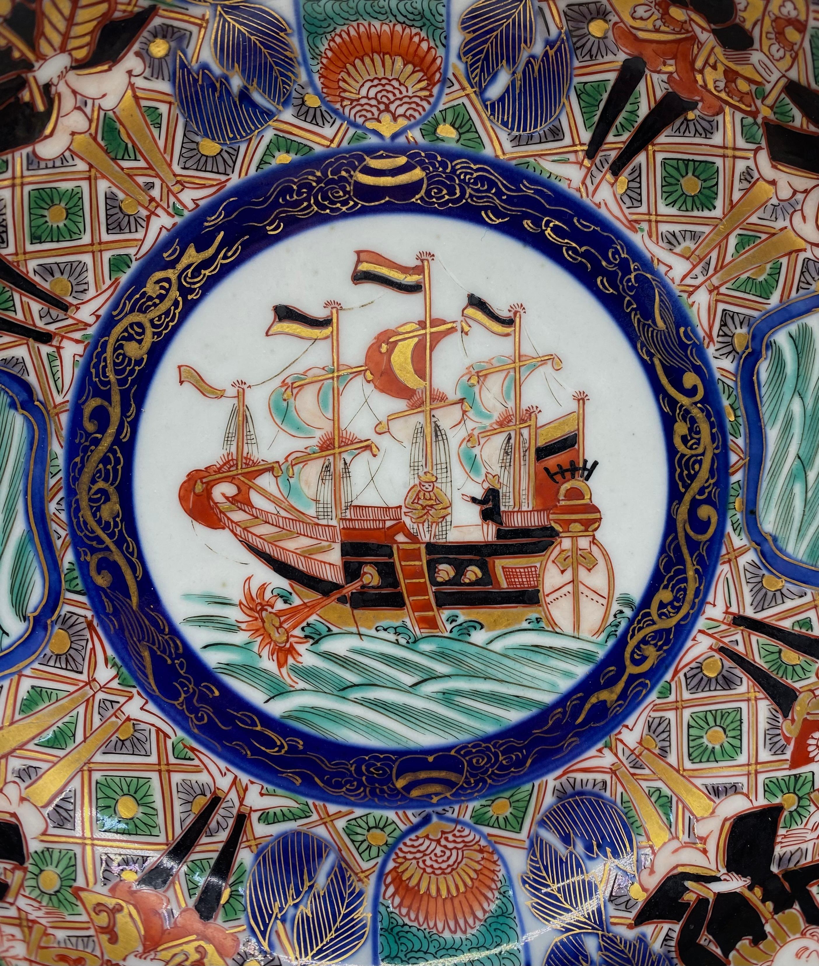 Japanese porcelain ‘Black Ship’ shallow bowl, 19th Century, Meiji Period. The bowl, well painted to the centre, with a circular panel, containing a Dutch merchant ship, firing a canon, within a cobalt blue surround, painted in gilt with two dragons,