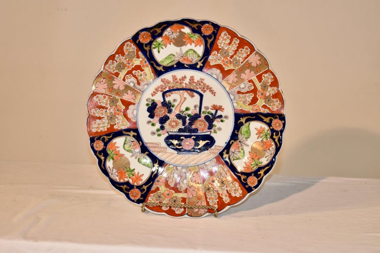 Circa 1900 Japanese hand painted Imari charger. The charger is hand painted in an array of spectacular colors and has a central lozenge with a potted plant, surrounded by a fan design, each part of the fan decorated with intricate patterns for a