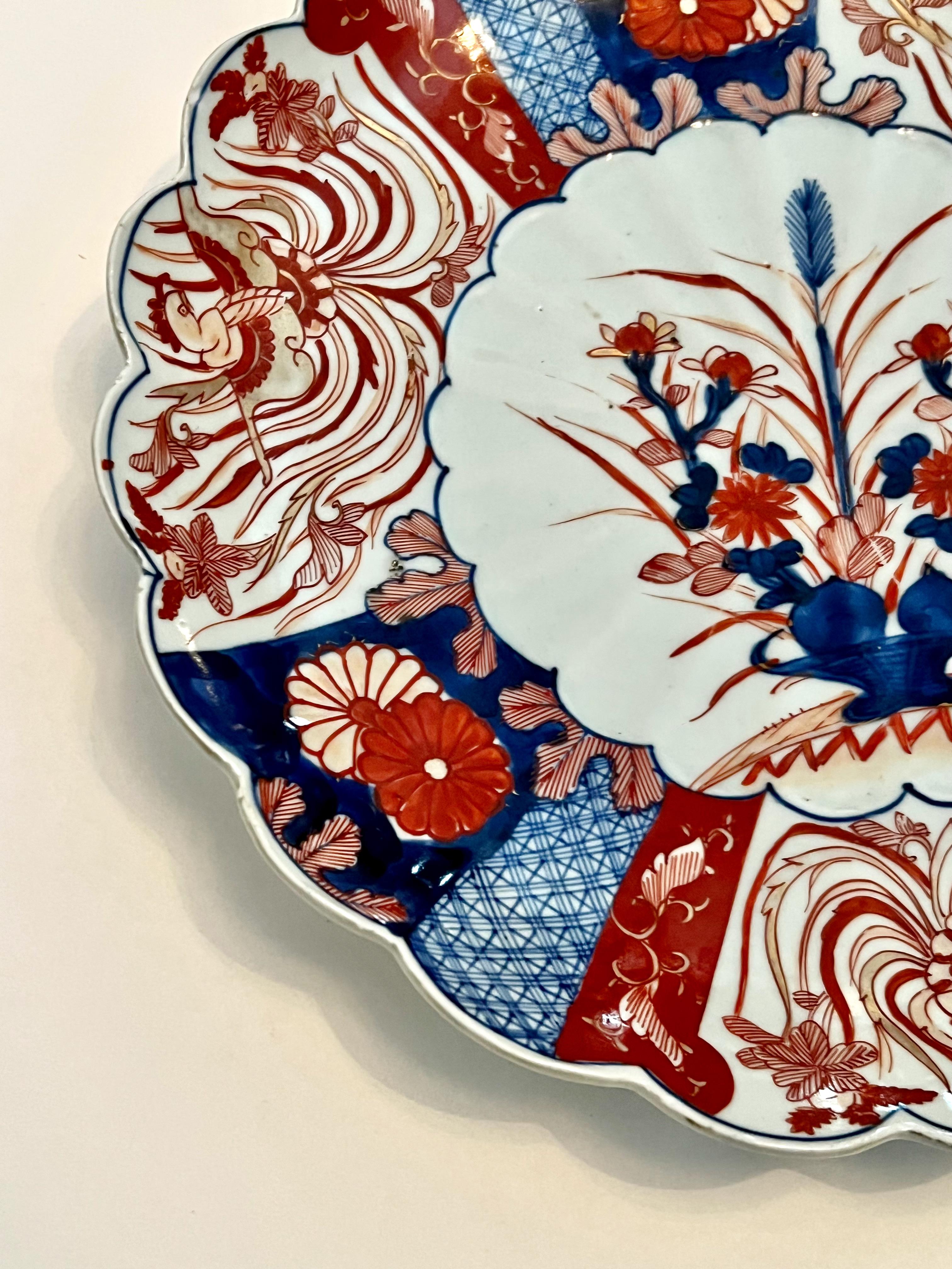 This is a classic example of a Meiji period imari charger. The charger measures 12 inches in diameter and features a central flower basket reserve surround with diapering and 3 hoho bird reserves. The back of the charger features an uncommon pattern