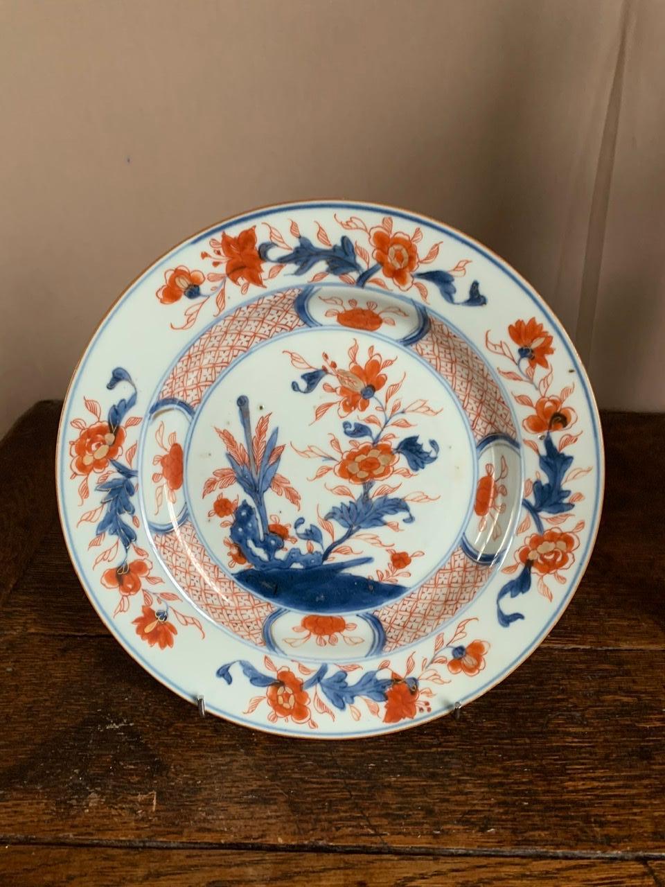 Beautiful Chinese porcelain plate with imari decoration. On this plate, the background is white, there is a blue outline, with blue and red floral decorations. Imari porcelain is actually a Japanese porcelain production site on the island of Kyushu,