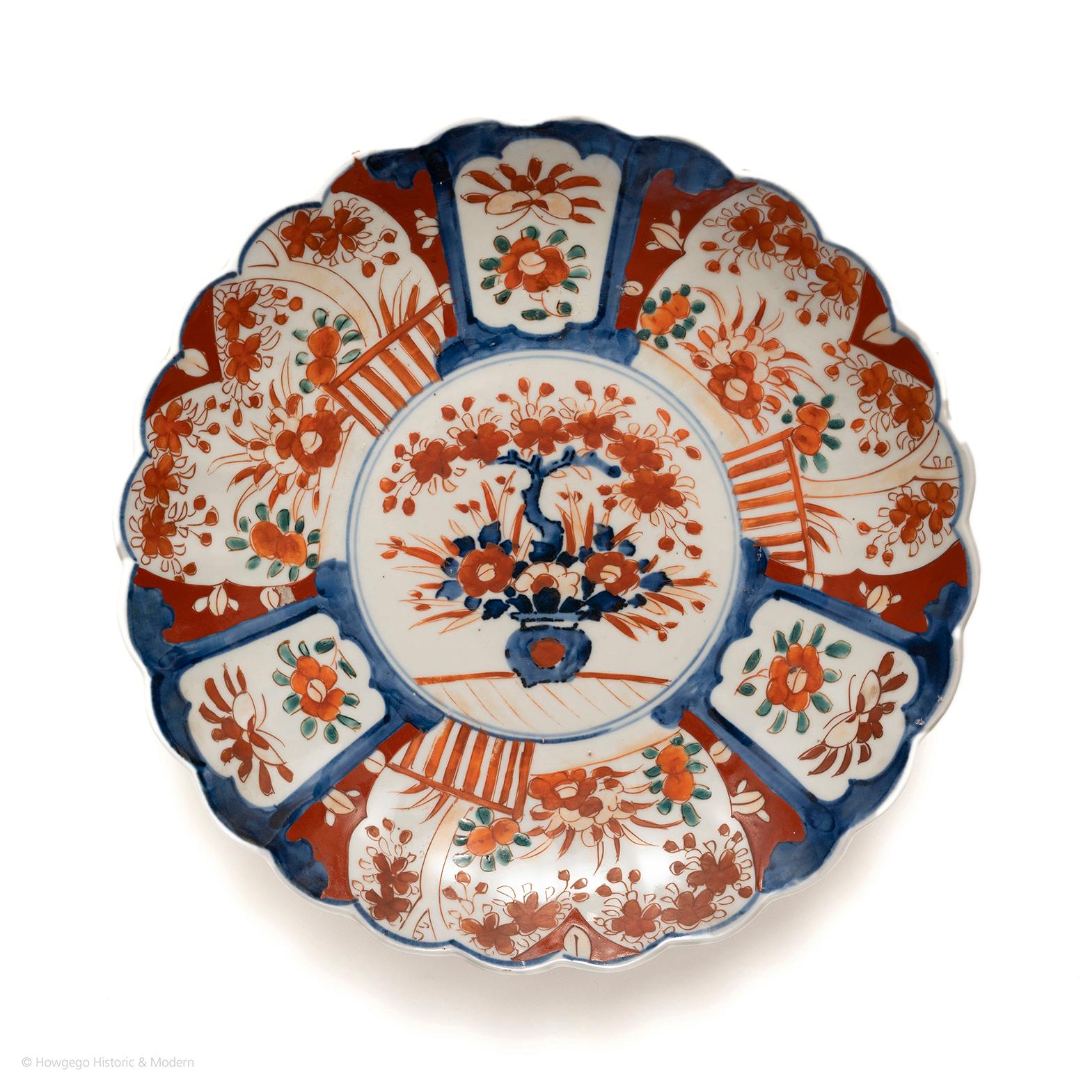 Exceptional 18th century Imari lobed dish. The centre painted with a vase of flowers and a bonsai tree. Surrounded by a double circle border and three large vignettes of a fenced garden with trees and flowers and stylised floral vignettes
