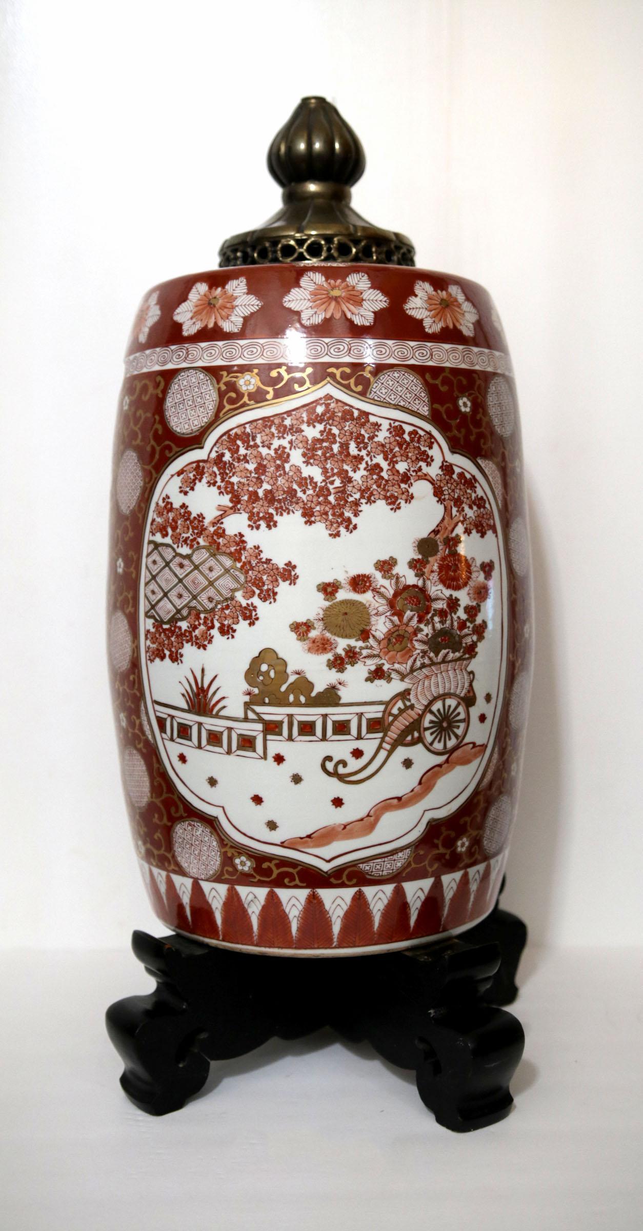 Un vaso giapponese in porcellana dorata e montata in ottone con una base in legno ebanizzato con un caratteristico motivo Imari di fiori, medaglioni e tocchi d'oro.
La tavolozza Imari stilizzata presenta un grande medaglione lobato con un cesto a