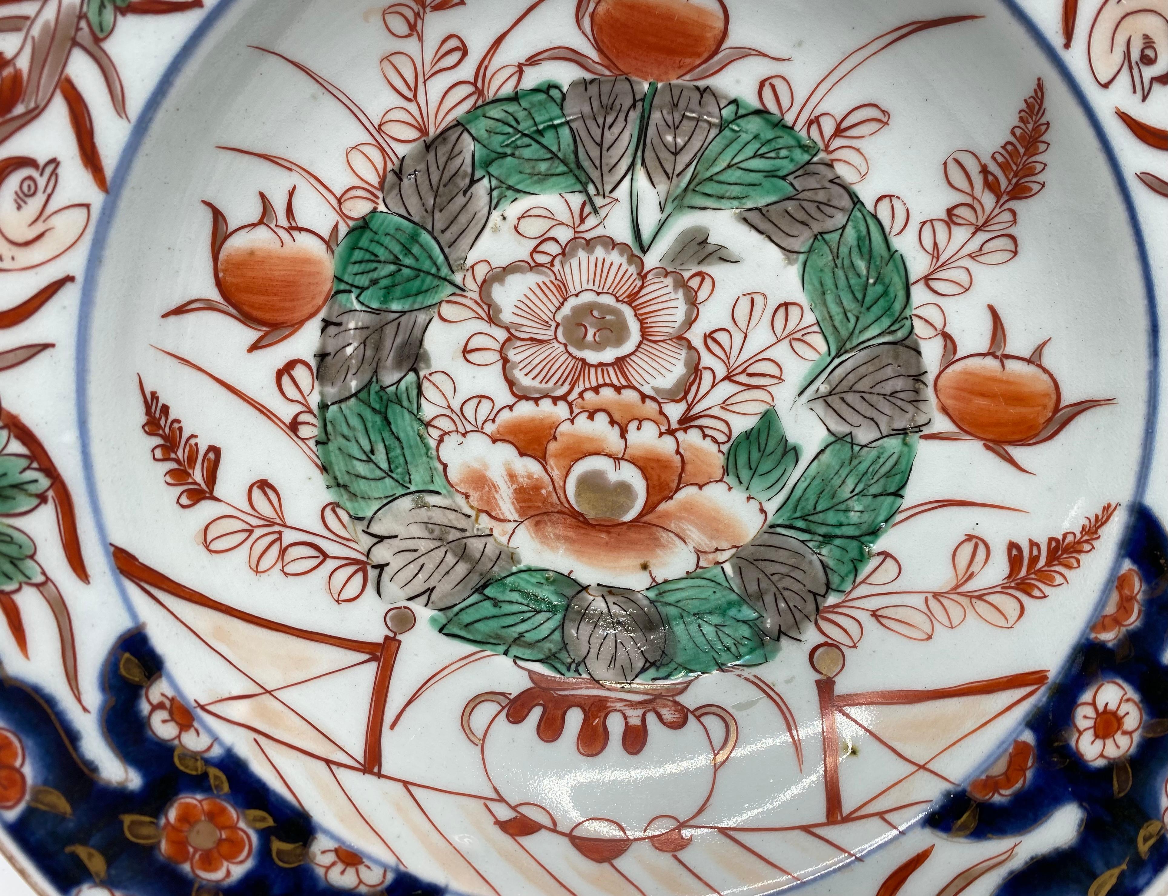 Japanese Arita porcelain barbers bowl, c. 1700, Genroku Period. Well painted in Imari colours, with an exuberant display of flowering plants, in a jardiniere, on a terrace. The border with shaped panels contains birds, divided by stylised flower