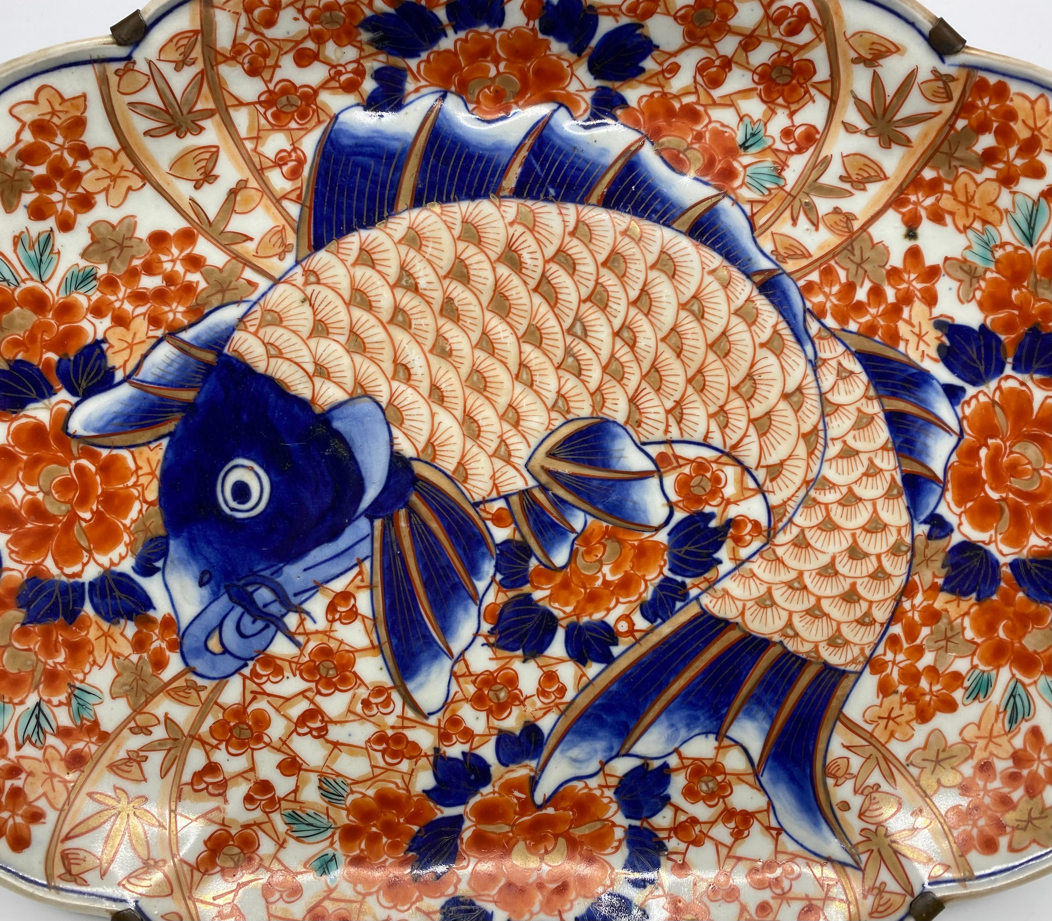 Japanese Imari porcelain Carp dish, Arita, c. 1890, Meiji Period. The canted rectangular dish, moulded to the centre with a large carp, in low relief, hand painted in typical Imari colours, and heightened in gilt. All upon a complex ground of