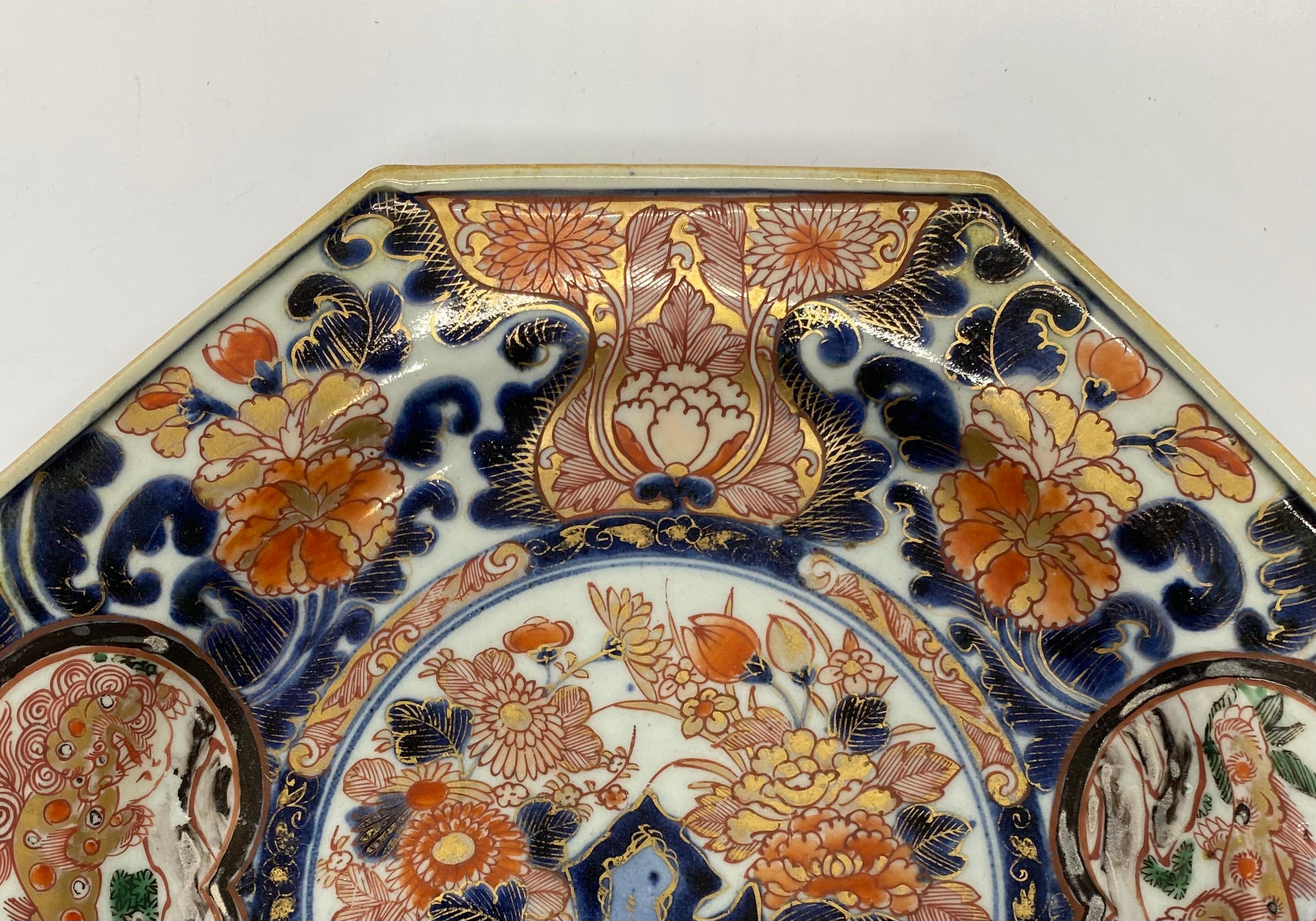 Japanese ‘Imari’ porcelain dish, Arita, circa 1700, Genroku Period. The hexagonal shaped dish, painted to the centre, with a large jardiniere, with a flowering plant, upon a terrace. The broad border, painted with panels of karashishi running over