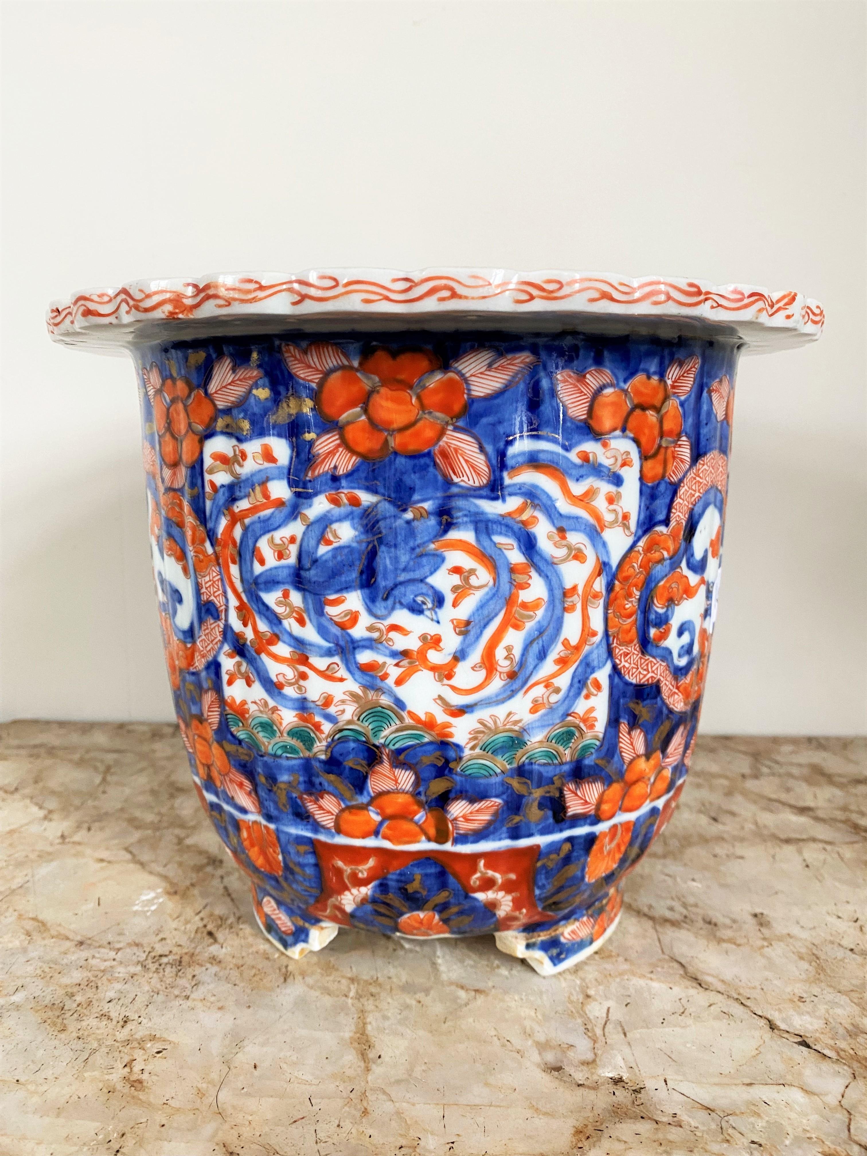 Beautiful porcelain planter decorated with imari. On this flowerpot, the background is blue, there are reserves in which appear a dragon and a bird surrounded by red flowers. The upper part of the porcelain is decorated with a red frieze on the