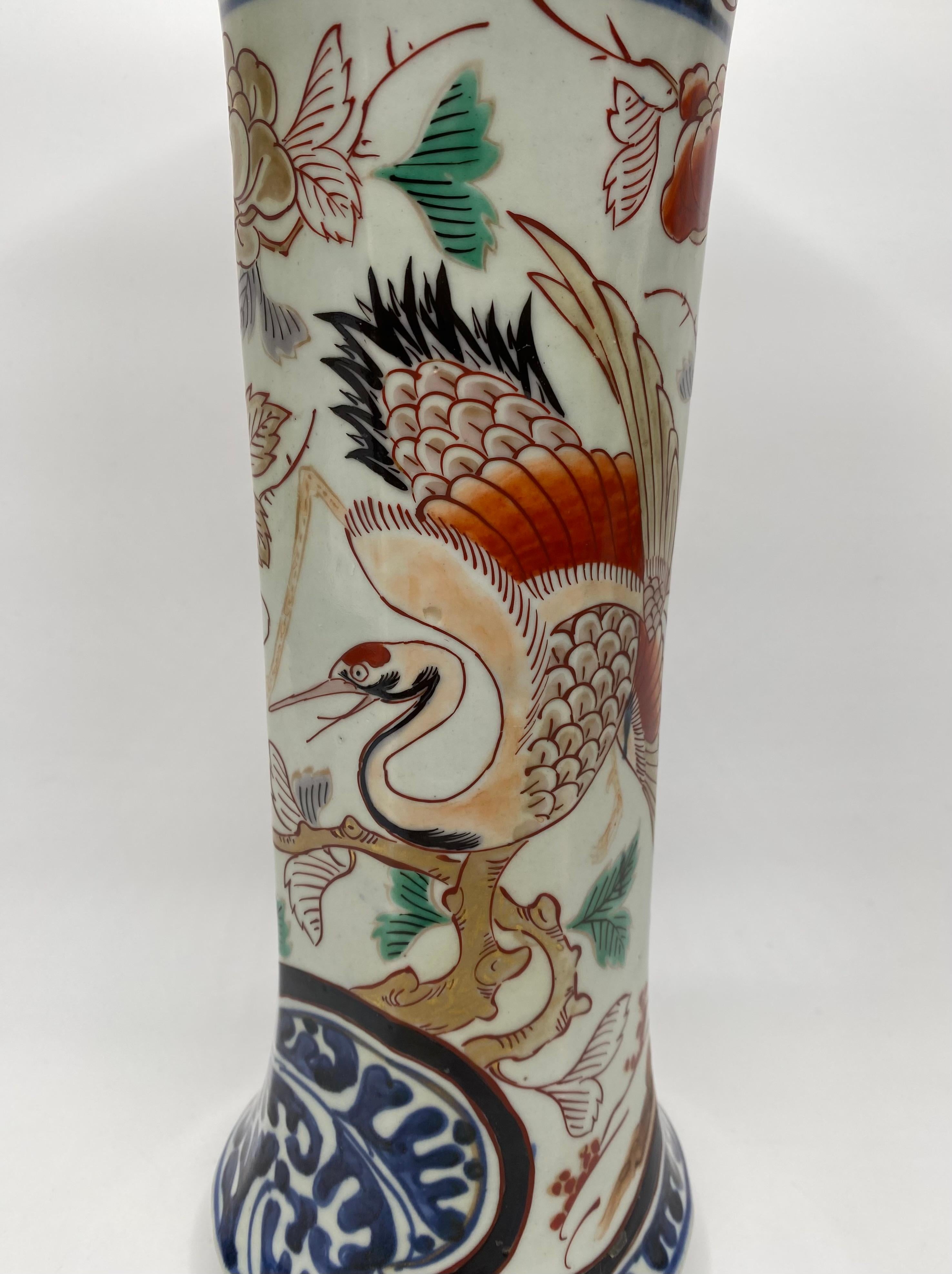 Japanese Imari porcelain trumpet vase, Arita, c. 1700, Genroku Period. The tall octagonal vase, well painted with a crane flying before a flowering tree, above a ground of underglaze blue karakusa scroll.
The neck painted with two small panels