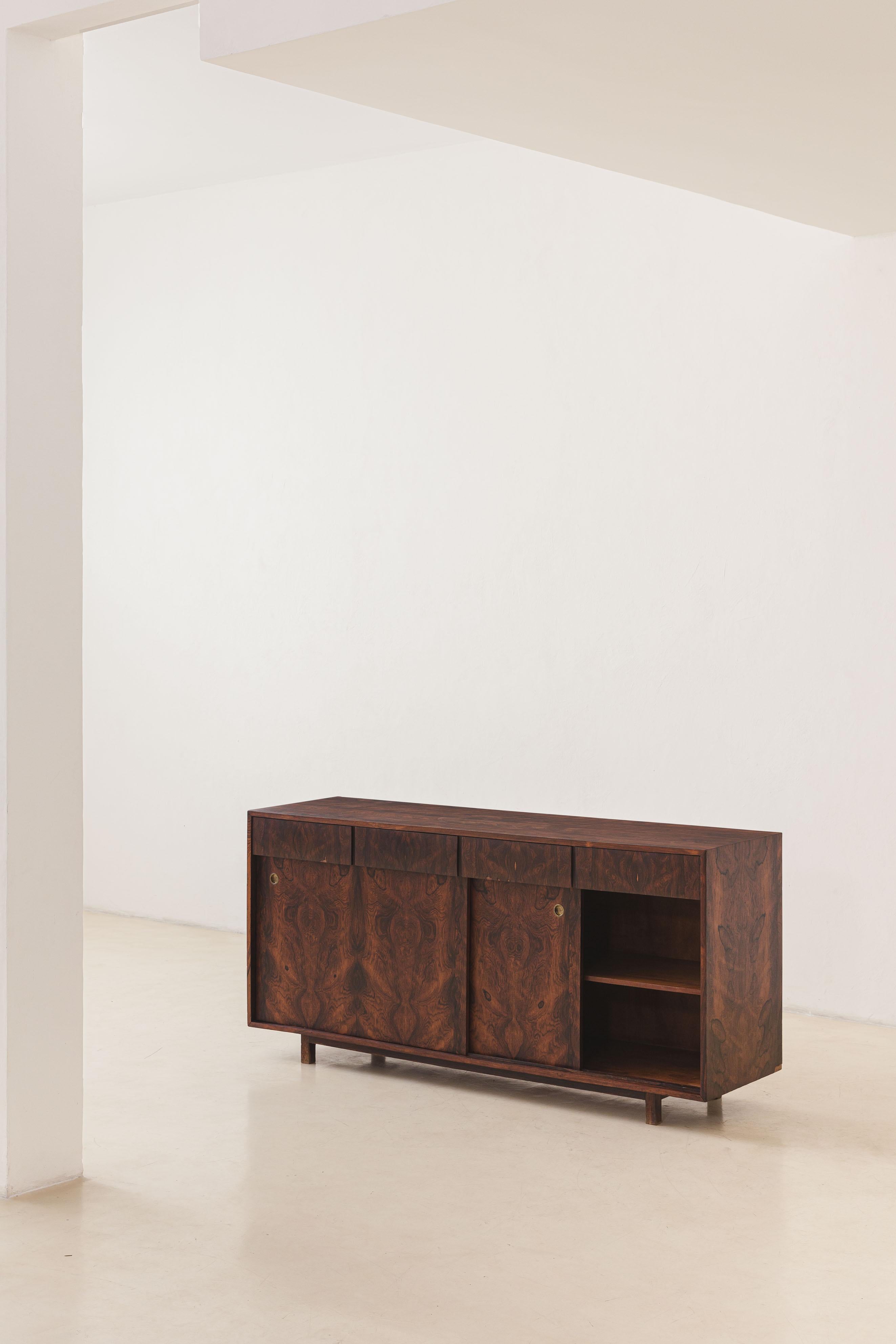 This Imbuia credenza was produced by the Brazilian company Celina Decorações in the 1960s. It consists of a very well-constructed piece composed of two large compartments with sliding doors and four drawers. This is a compact piece, ideal for more