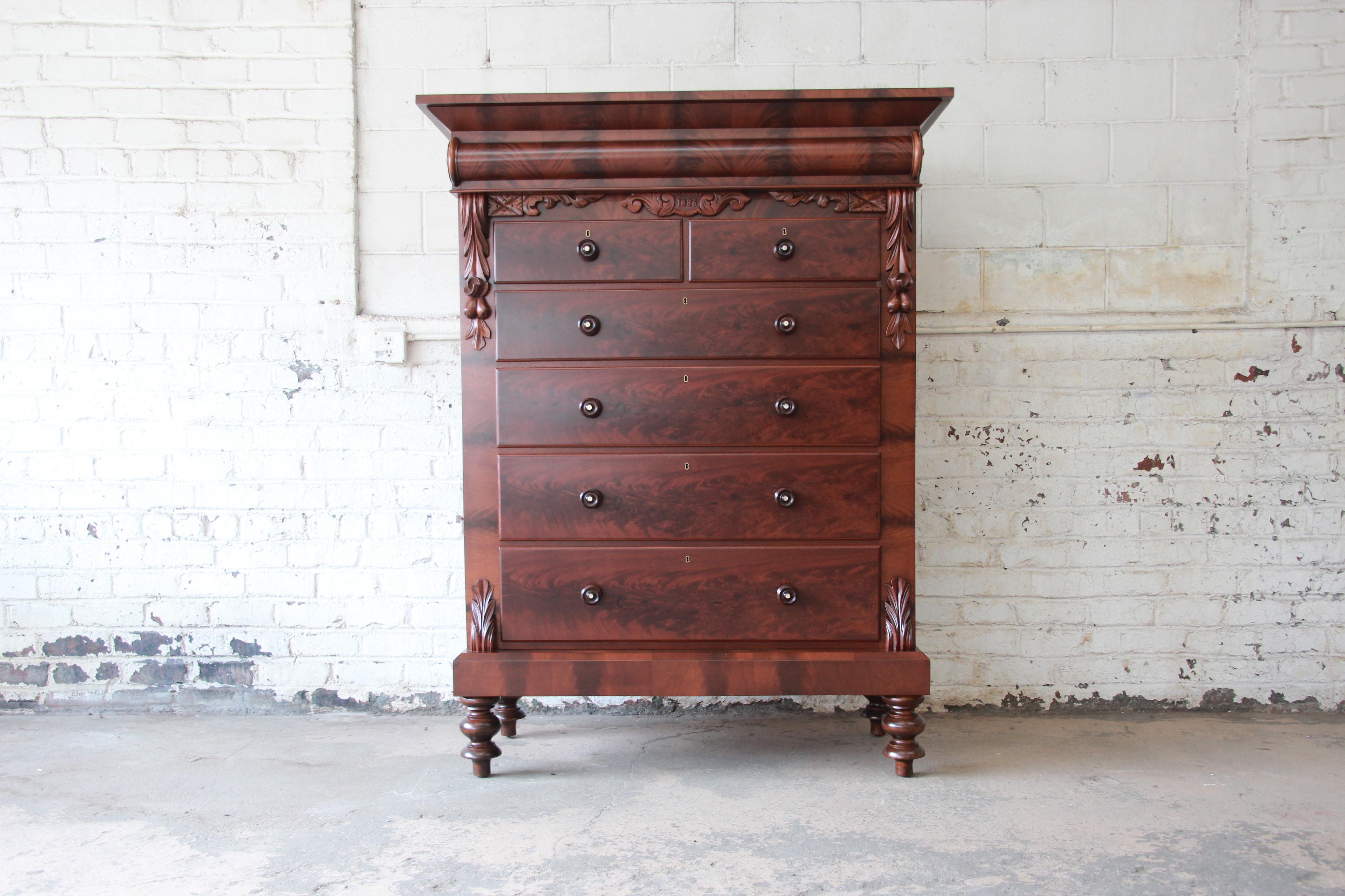 An immaculate and monumental American Empire flame mahogany chest of drawers. The chest features stunning wood grain and unique carved details with a floral motif. It offers ample room for storage with six deep dovetailed drawers, as well as a large