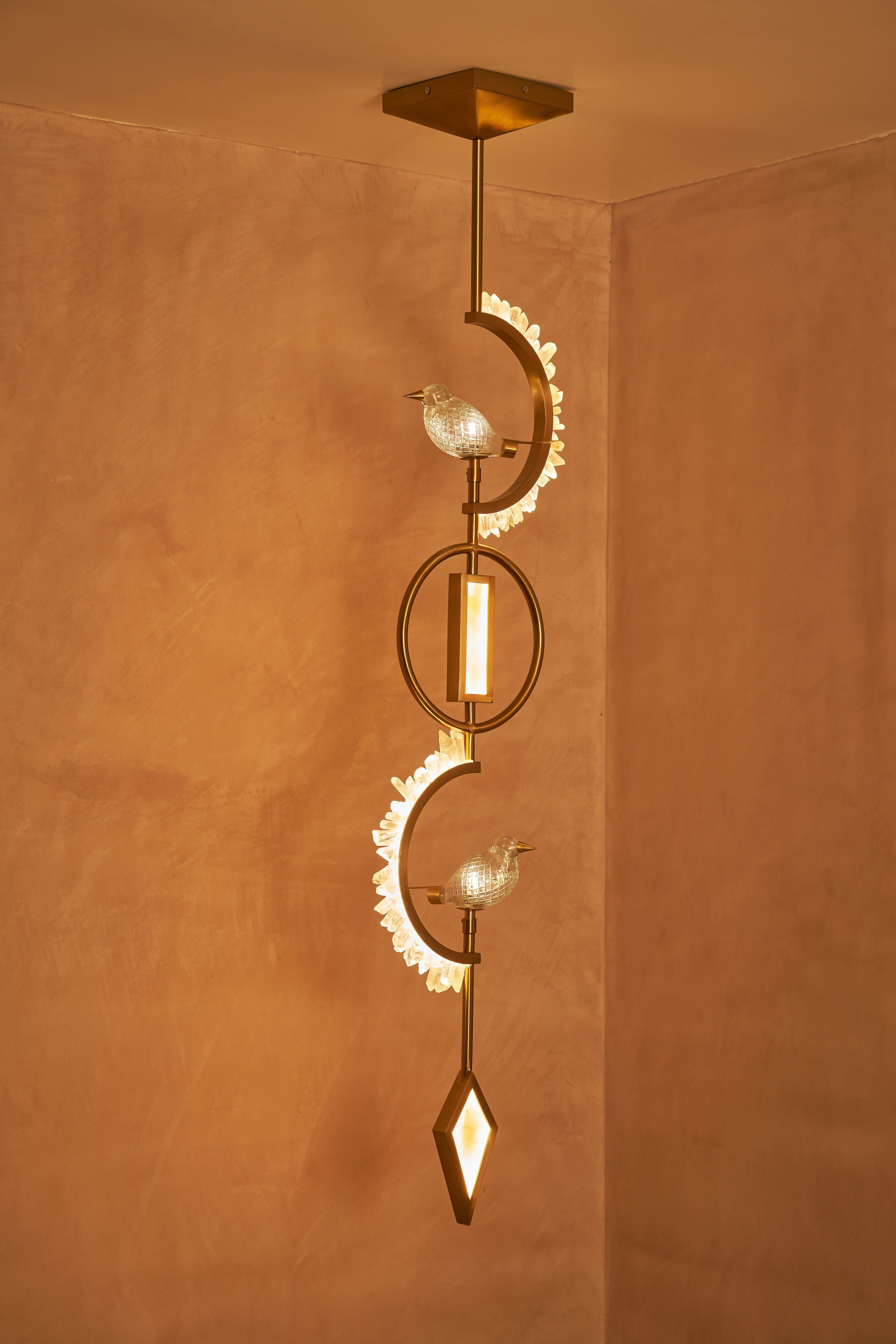 Eleganza per i tuoi interni con questa splendida applique che combina magistralmente eleganza e maestria. Caratterizzato da una disposizione verticale di cornici geometriche rifinite in ottone, questo pezzo mette in mostra due uccelli di cristallo