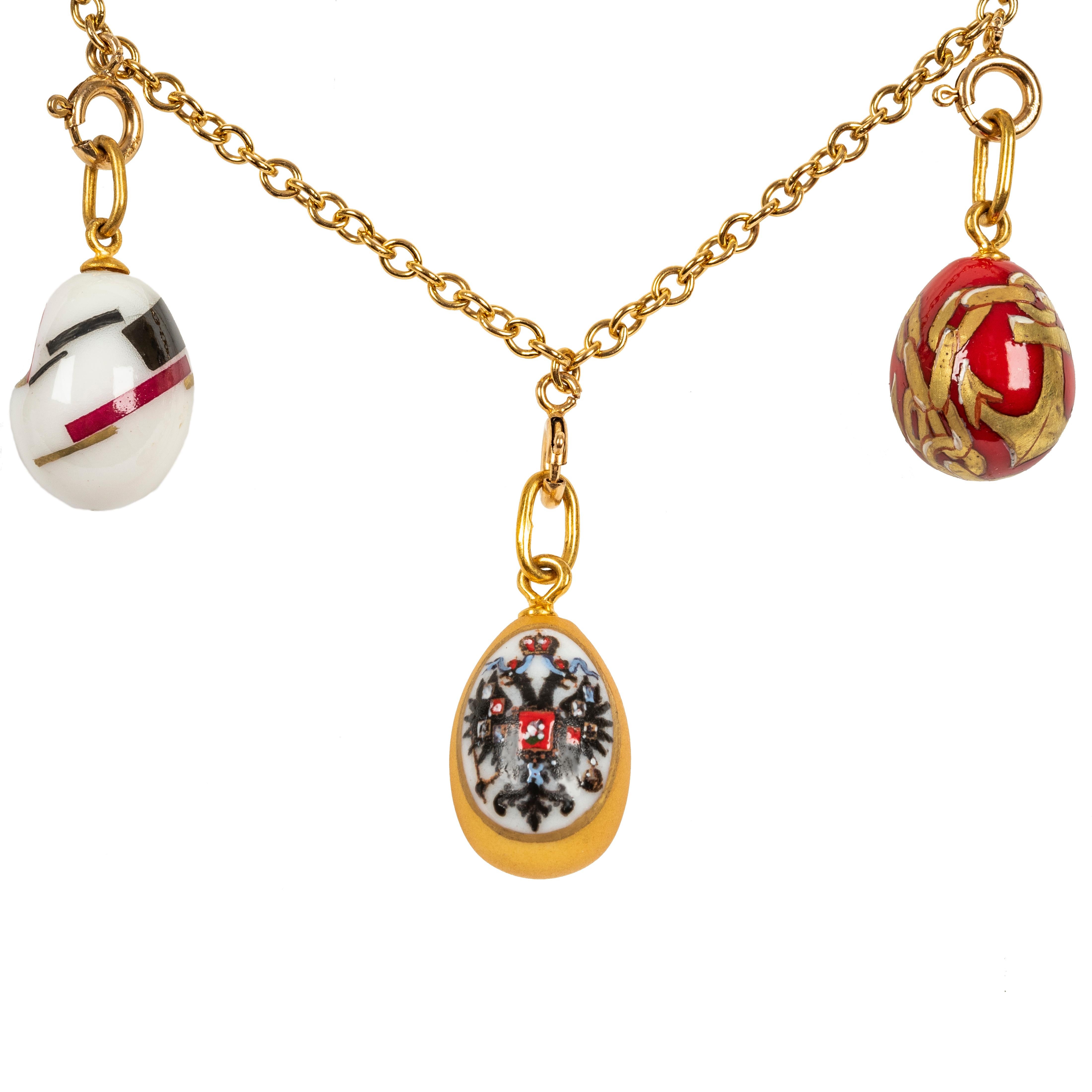 Ce magnifique collier d'oeufs de Pâques est conçu comme une chaîne à maillons classique suspendant neuf pendentifs d'oeufs peints à la main et provenant de Saint-Pétersbourg, en Russie. En porcelaine colorée représentant un aigle bicéphale des