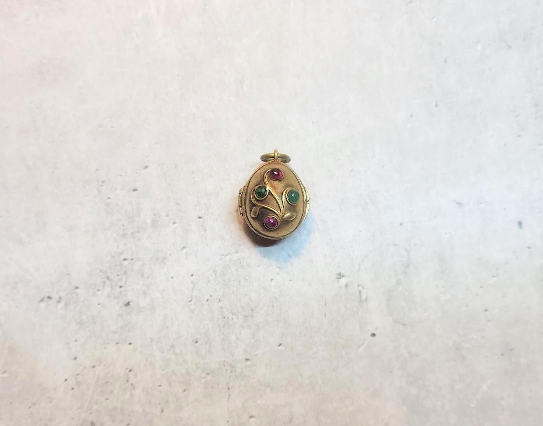 Presenting a stunning locket-pendant designed in the shape of a Russian Imperial gilt silver 84. The pendant is engraved on both sides with a floral motif, decorated with natural rubies and emeralds.

This Imperial locket-pendant, a rare and