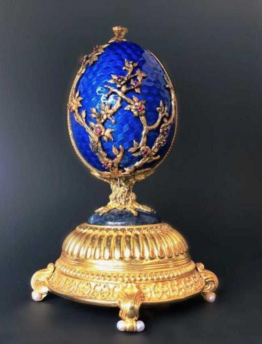 Musical Stravinsky's fire bird suite, egg shell solid silver with blue cobalt enameling, 24-karat gold over sterling apple blossom designs entwining egg, each with fully faceted ruby, 24 rubies in all, clasp on top with 2 cabochon rubies, opening to
