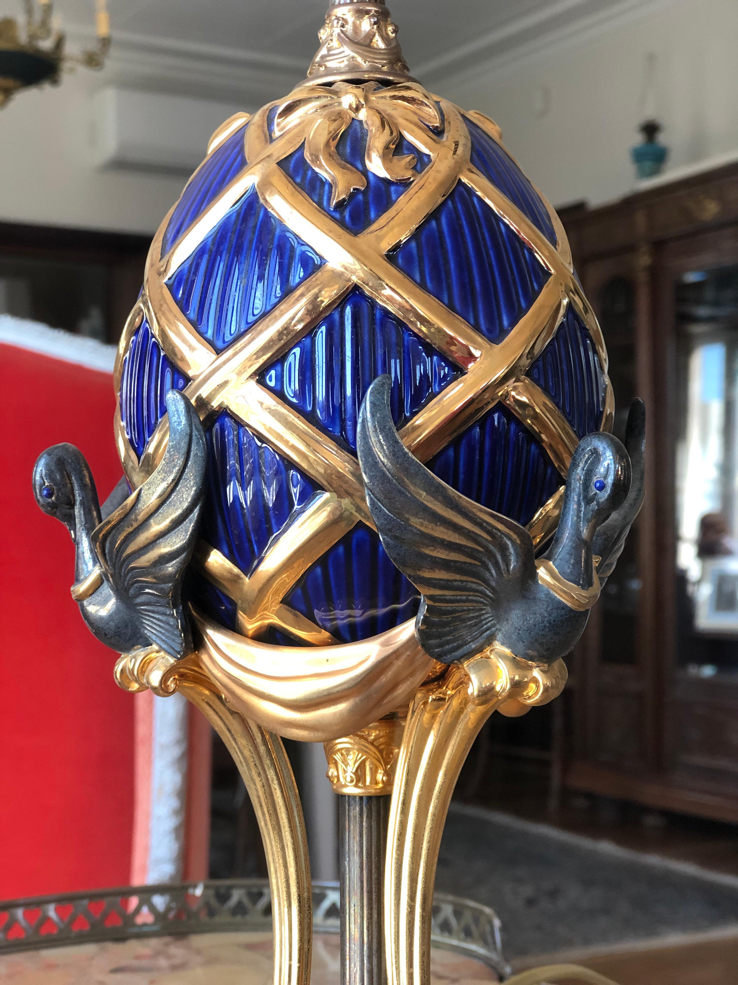 Rare Faberge egg form lamp made by the Franklin Mint in cooperation with the House of Faberge. The porcelian egg is highlighted by w24kt gold with silver plate swans with lapis eyes. It measures 9 1/2