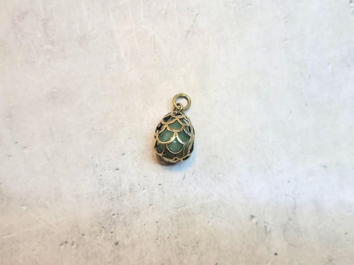 We present an adorable egg pendant in gilt silver with a green fluorite stone. The egg, carved from green fluorite, appears enclosed in a gilded cage. It is truly an enchanting piece of jewelry.
Behold not just any Russian silver jewelry item but a