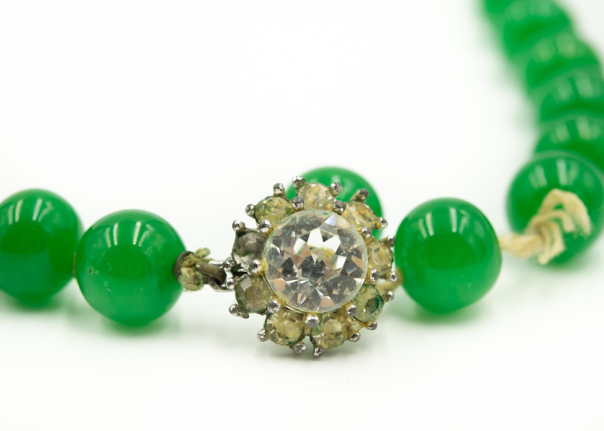 1950's Imperial green Peking glass beaded necklace hand knotted on string with a rhinestone clasp. The beads are approximately 9.75 mm, matched, and round. The color and look of the necklace simulates imperial jade. The necklace is 20 3/4