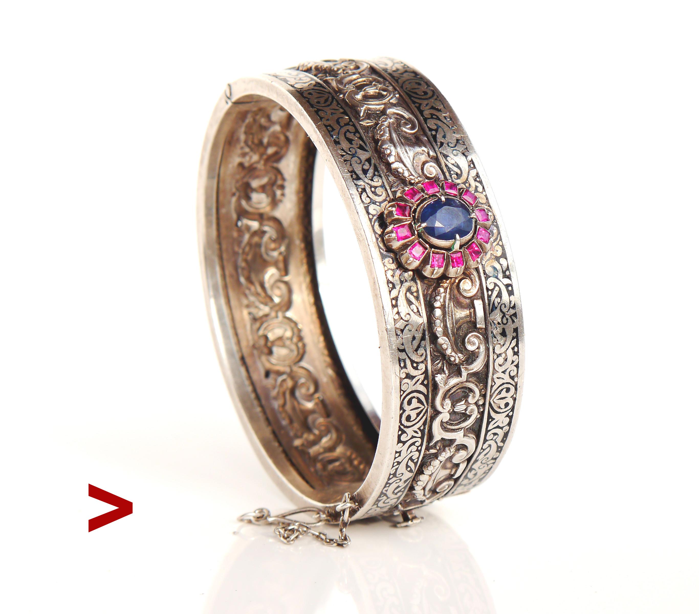Russian Imperial period fine bangle in 84 Silver.

Main attraction here is a Flower measuring 17 mm x 14 mm with natural and untreated medium Blue colored Sapphire 8 mm x 6.5 mm x 5 mm ca.2 ct surrounded with 12 baguette cut Rubies 2.25 mm x 2 mm