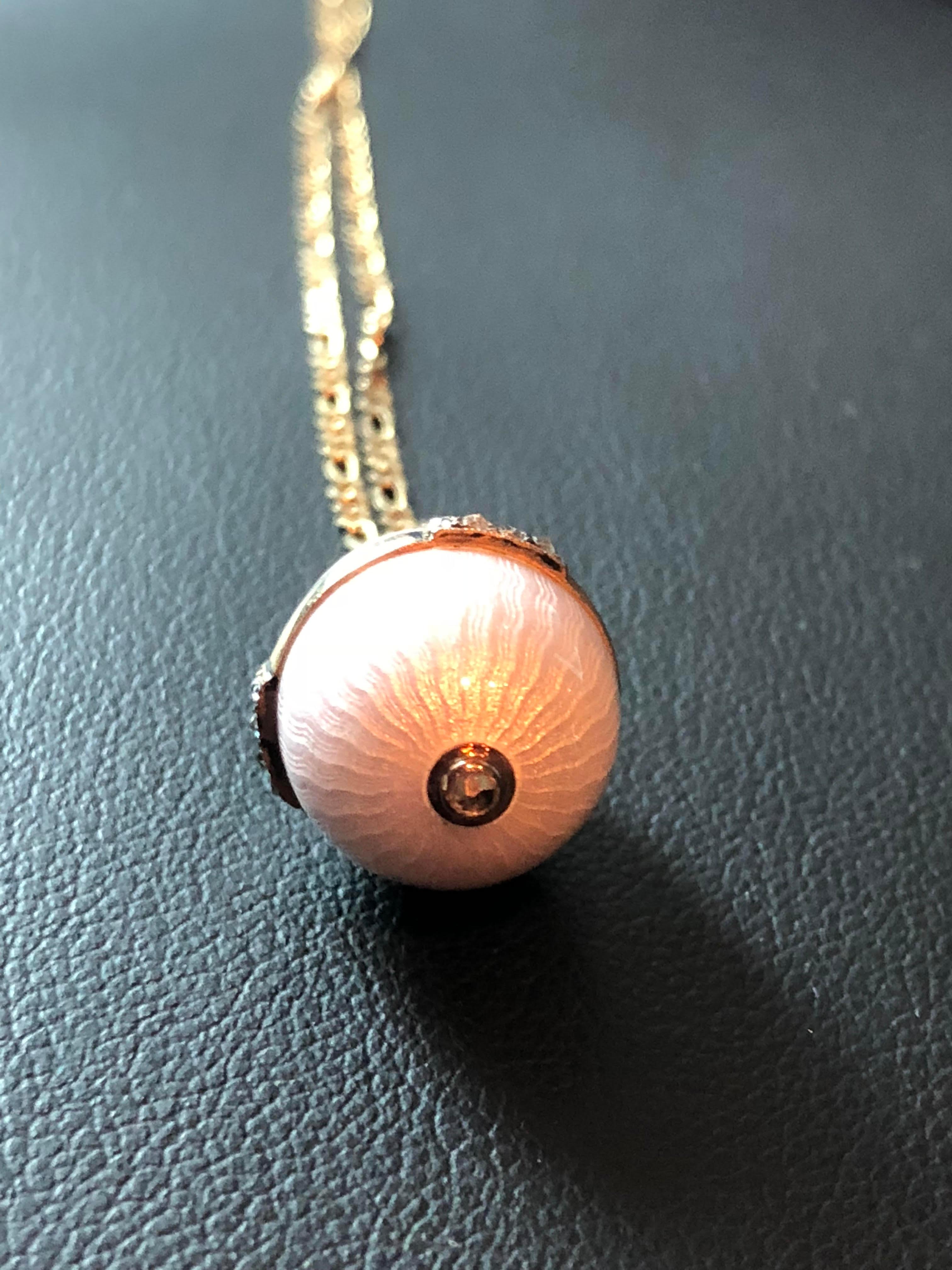 A fine miniature egg pendent by Andrew Anacov fully marked .The egg is modeled in silver with powder pink guilloche enamel with 14k gold fittings and finished , a gold band and around the middle is set with rose cut diamonds in miliram setting and