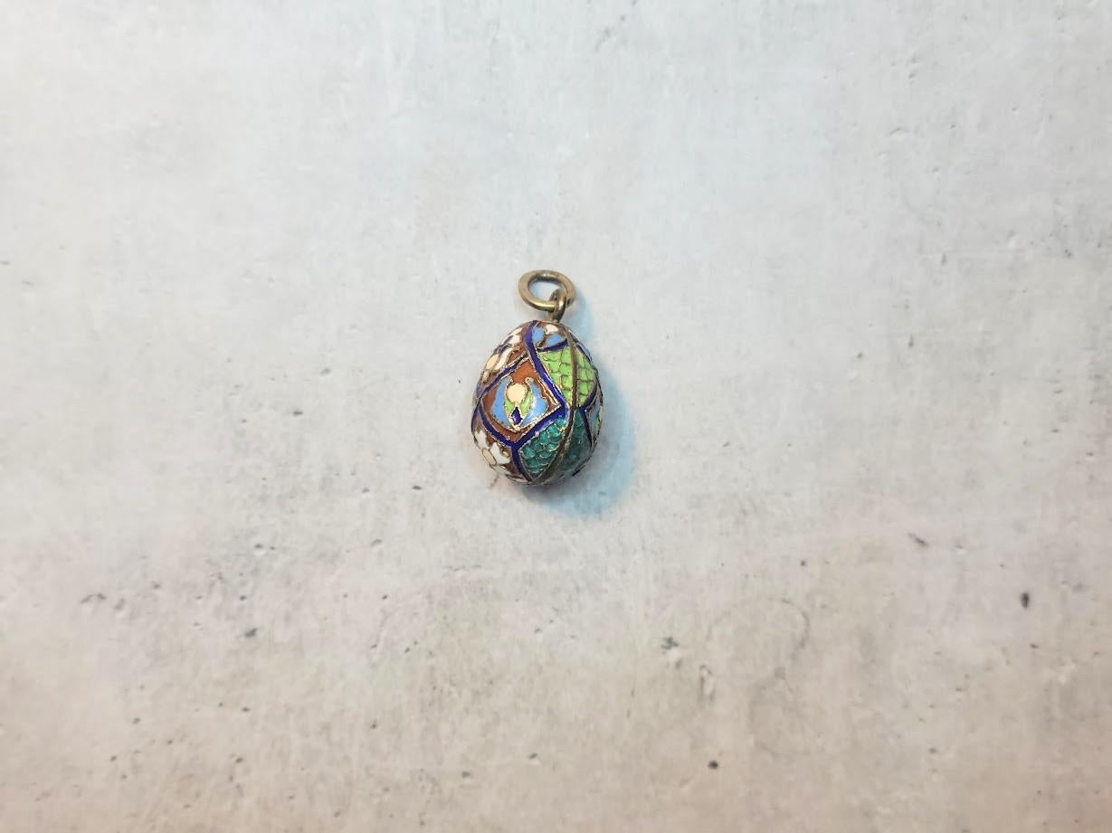 This antique Imperial Russian gilt silver egg pendant showcases colorful polychrome cloisonné enamels depicting floral, foliage, and geometric patterns.

Dimensions:
Height (excluding suspension ring): 24 mm
Width: 15.7 mm 
Weight: 4.65 gr

The