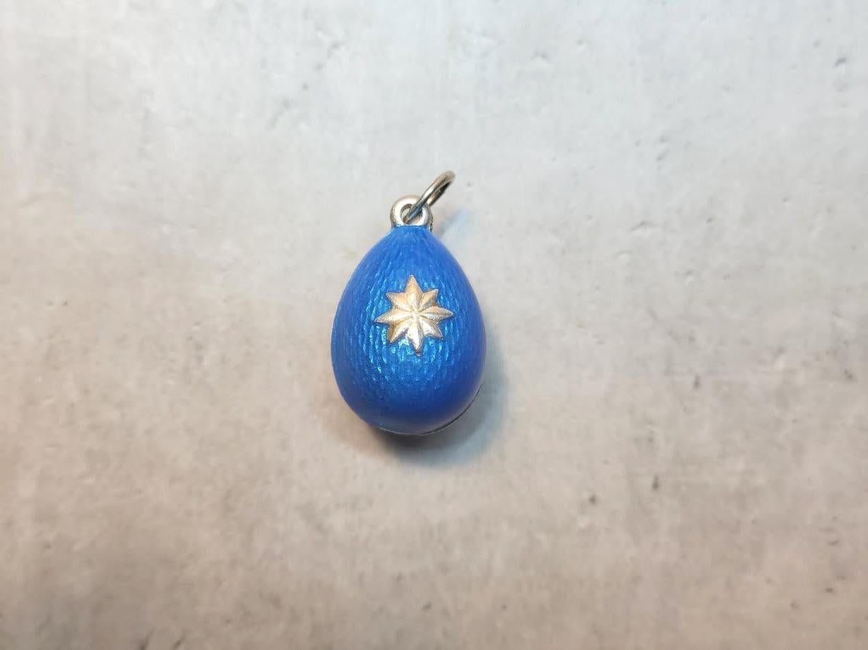This stunning, bright blue egg pendant, a rare and historically significant piece, was crafted by the renowned workmaster Phillip Theodore Ringe. It is a silver egg pendant, guilloche bright blue enameled and adorned with an unusual silver star on