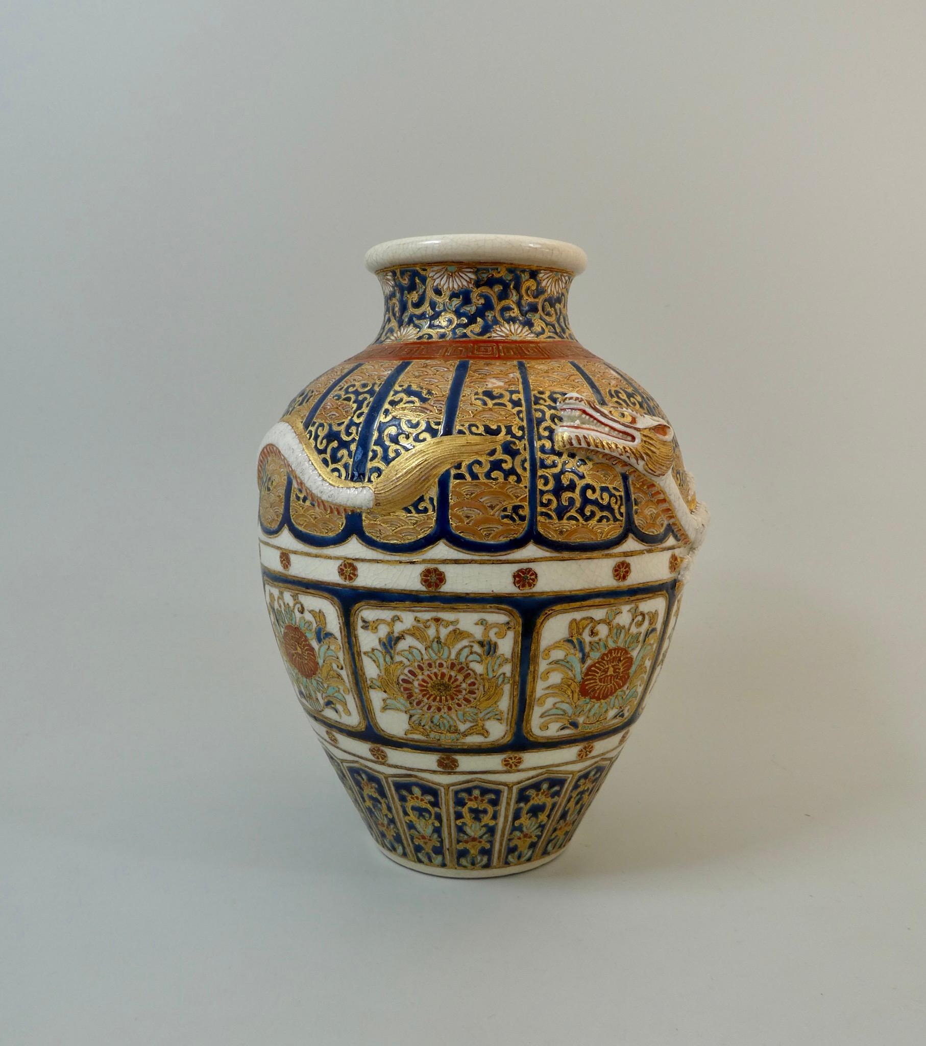 An Imperial Satsuma earthenware vase, circa 1870. Meiji Period. The baluster shaped vase, moulded with a dragon, flying over cobalt blue ground lappets, decorated with stylized waves, and scrollwork. Continuous panels containing stylized flowering